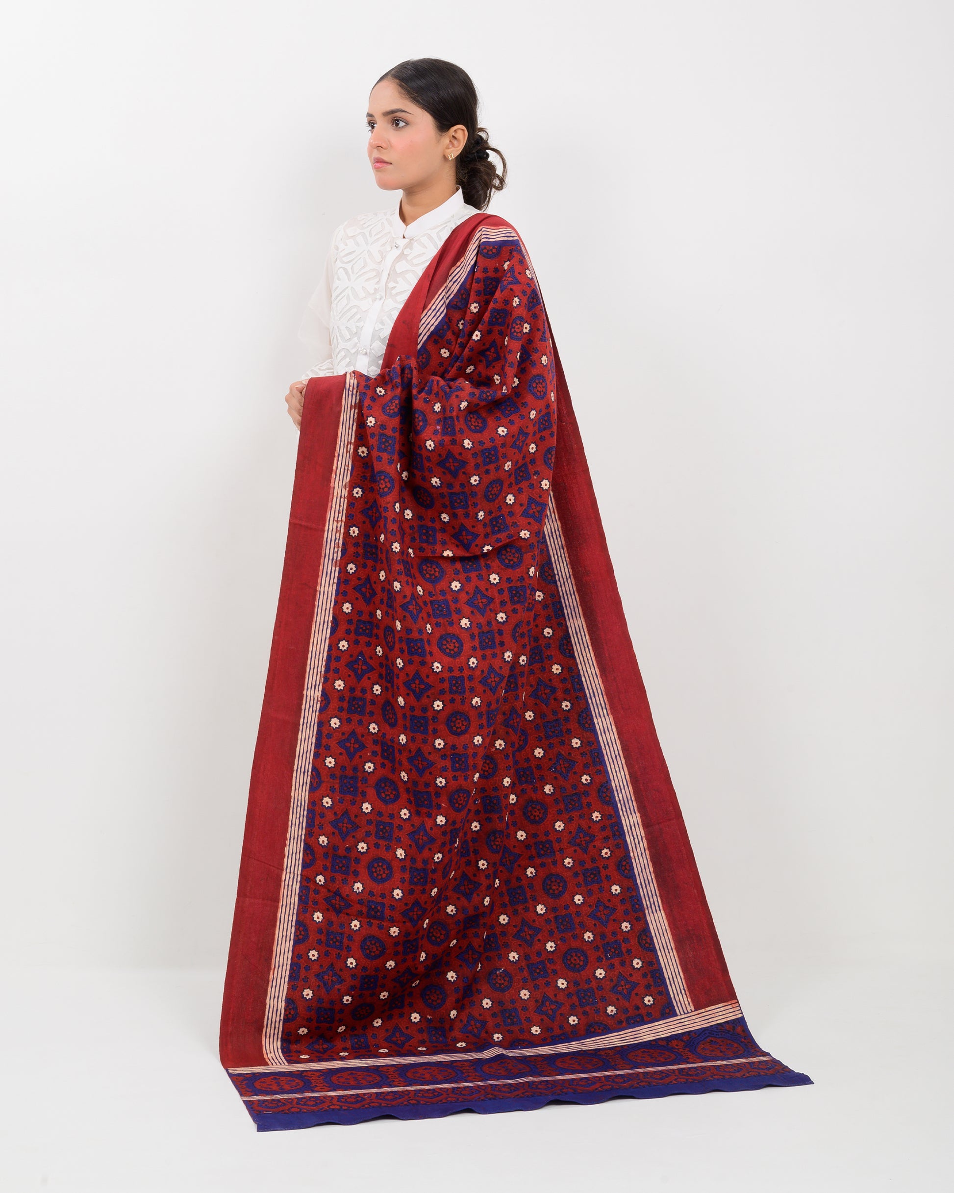 Woman holding a Sindhi traditional block print ajrak shawl against a white background