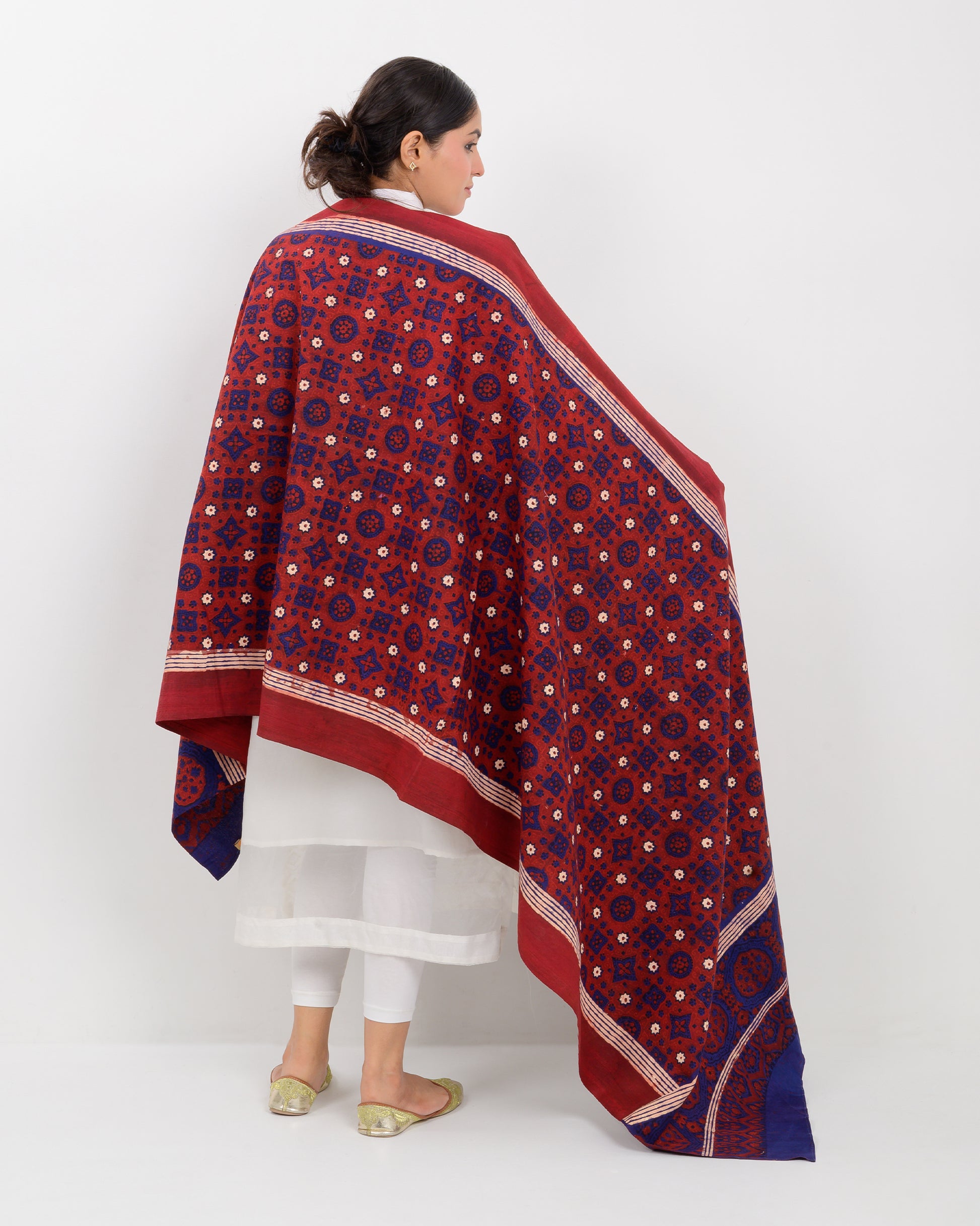 Woman holding a Sindhi traditional block print ajrak shawl against a white background