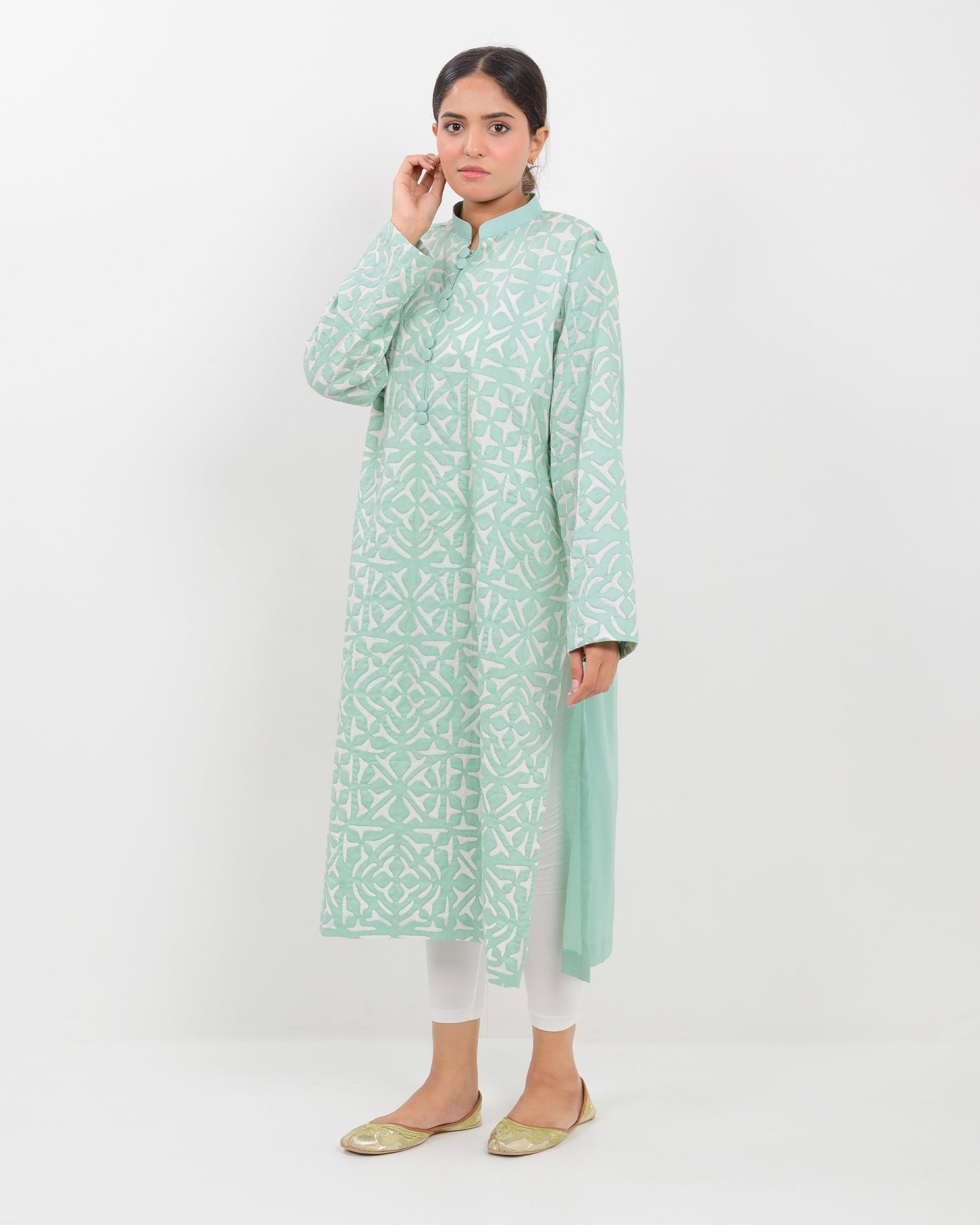 Woman wearing a light green applique cutwork craft shirt on a white background