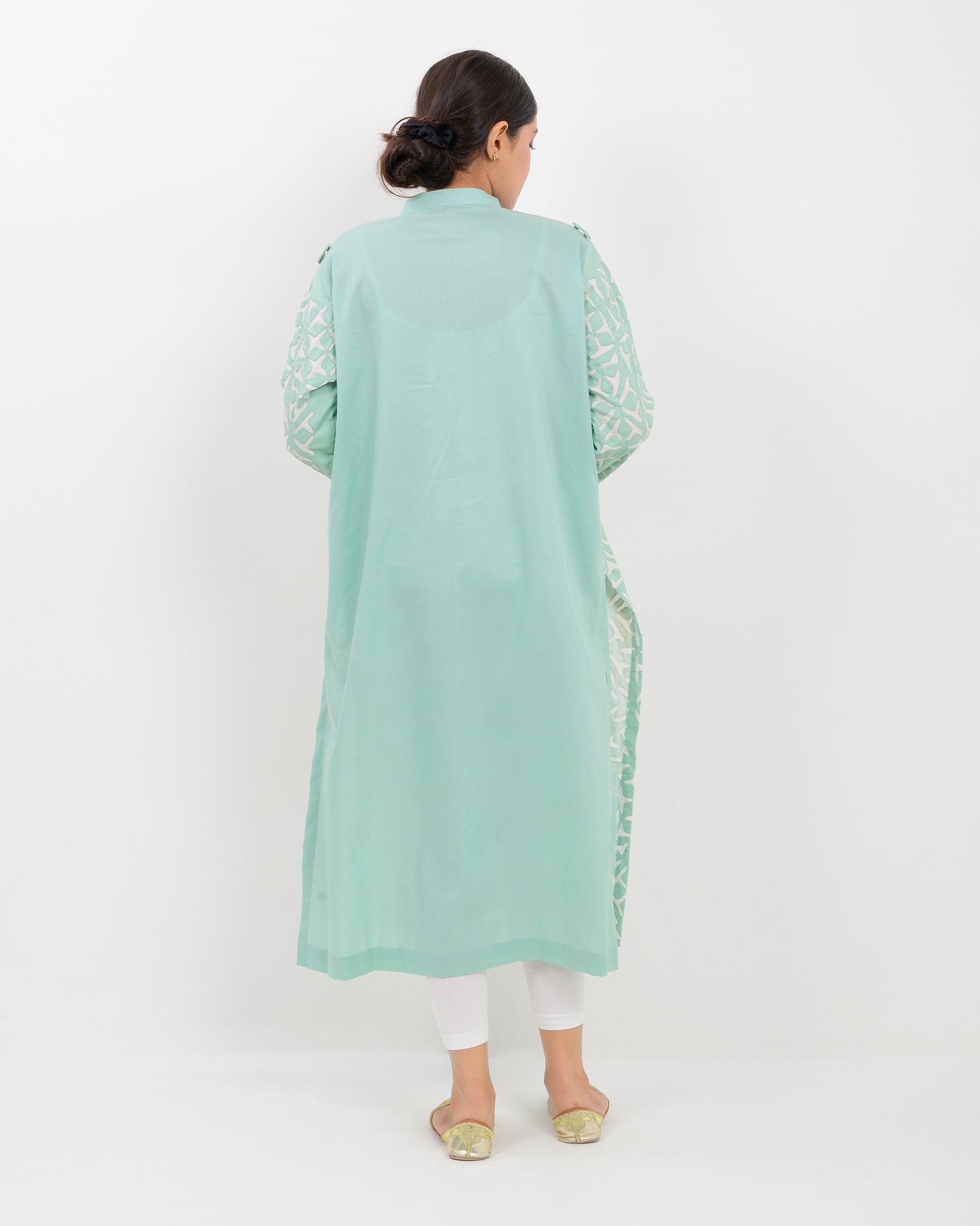 Woman wearing a light green applique cutwork craft shirt on a white background