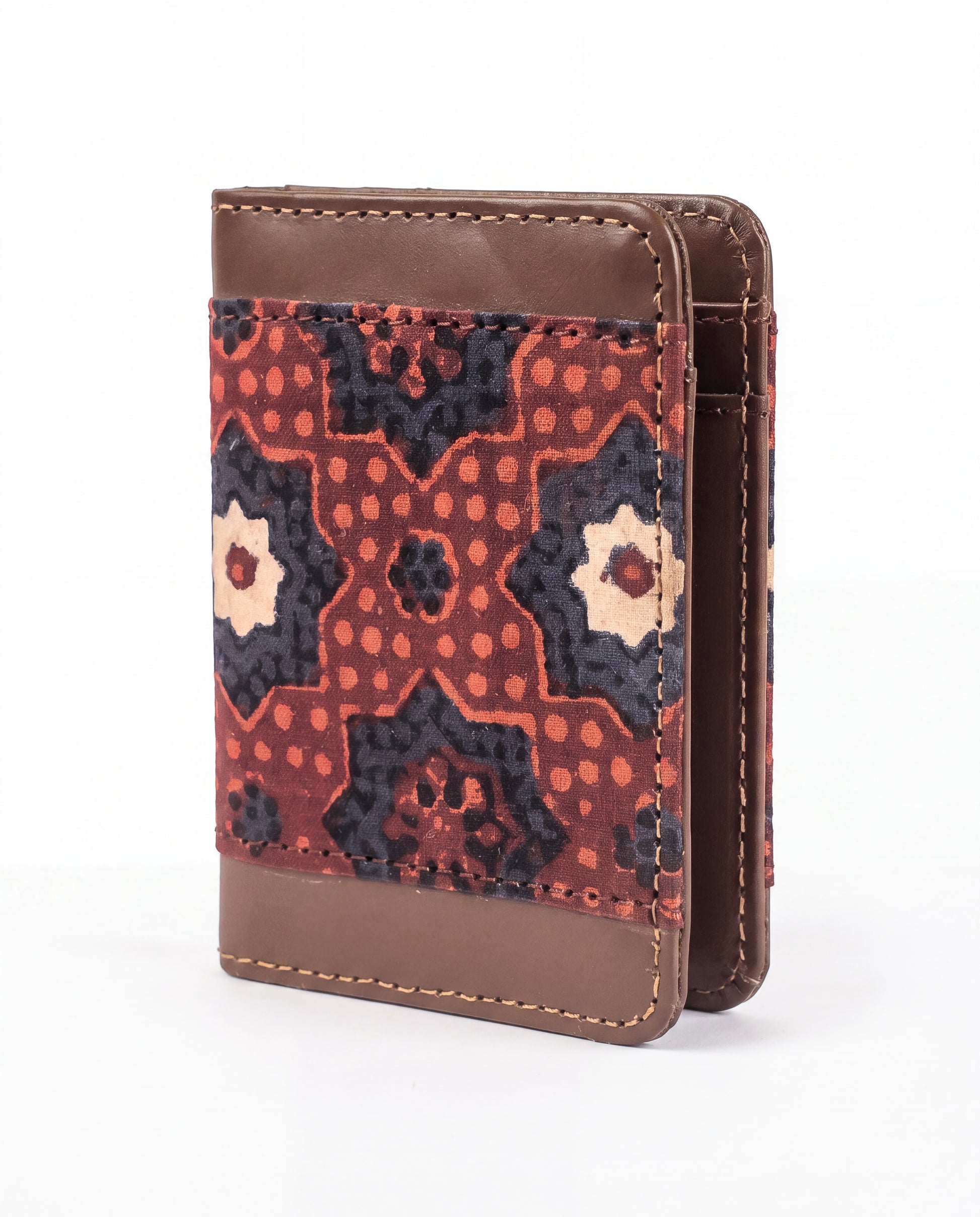 A small leather wallet with a geometric patterned fabric front panel, featuring brown leather trim and a reddish-orange, navy, and cream pattern.