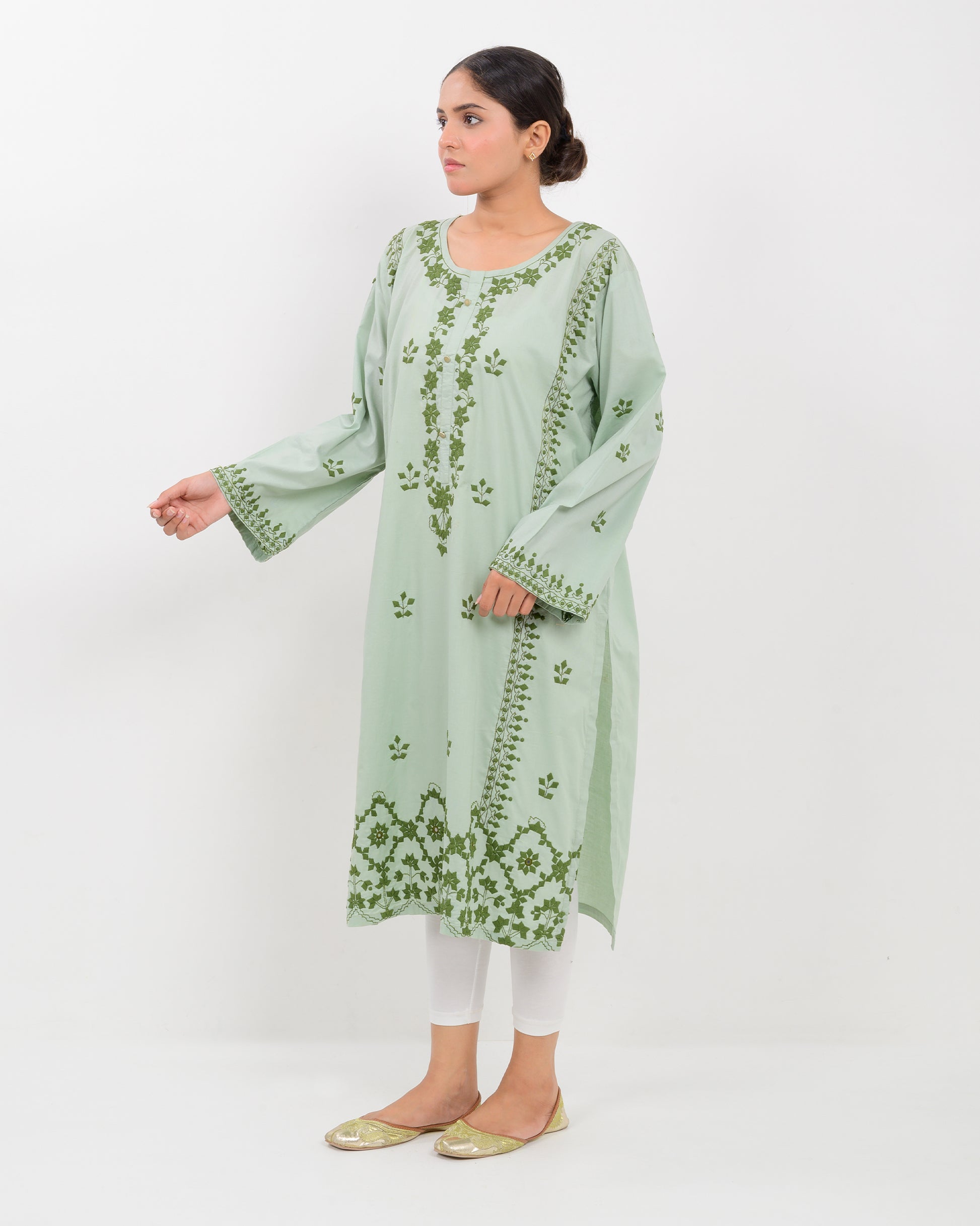Woman wearing an Applique cutwork green embroidered Shirt with white pants on a white background