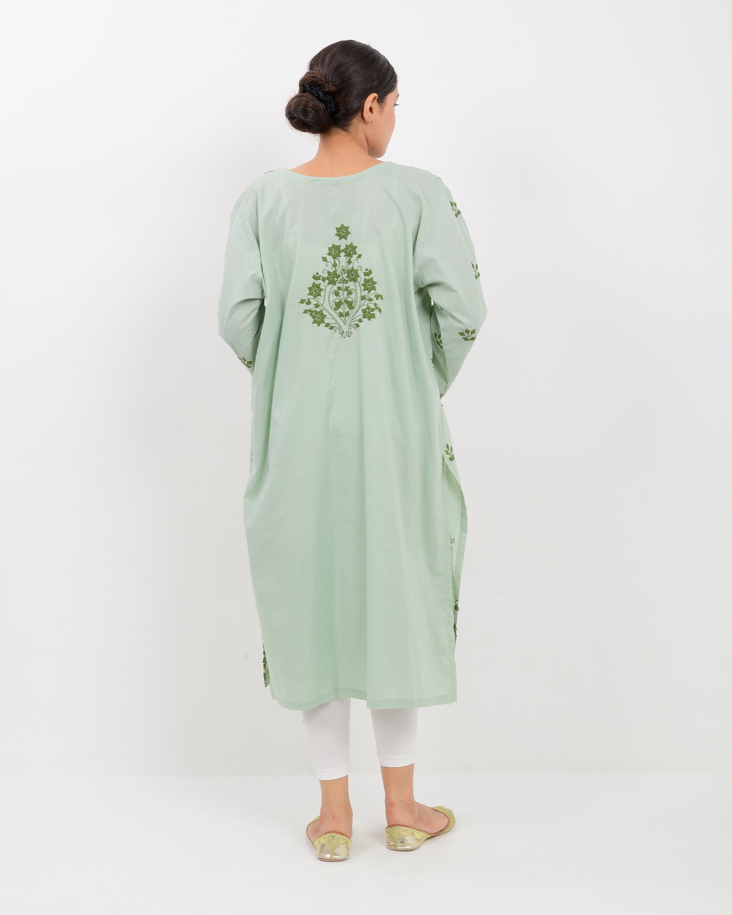 Woman wearing an Applique cutwork green embroidered Shirt with white pants on a white background