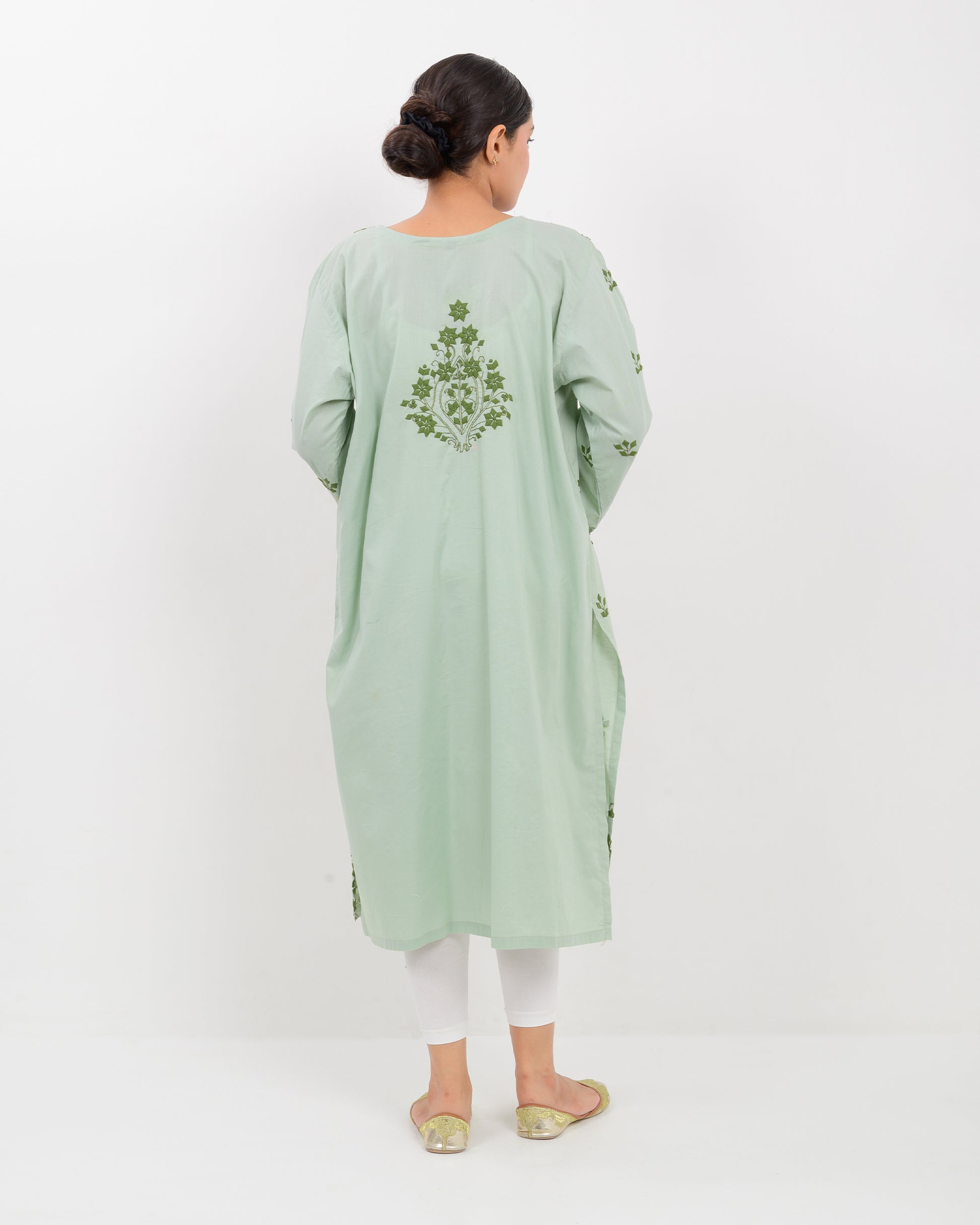 Woman wearing an Applique cutwork green embroidered Shirt with white pants on a white background