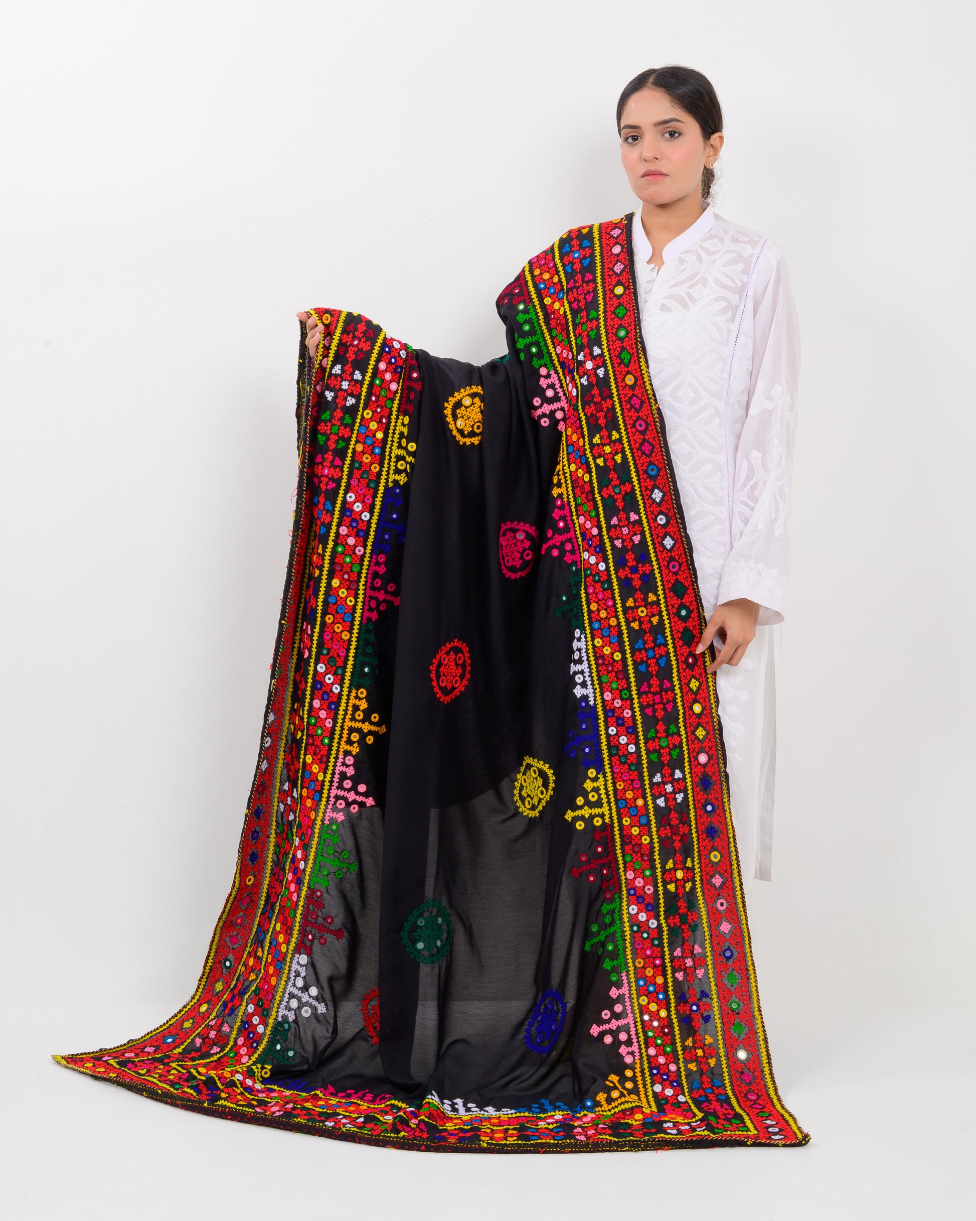 Woman wearing a black embroidered hummich mirror work shawl on a white background