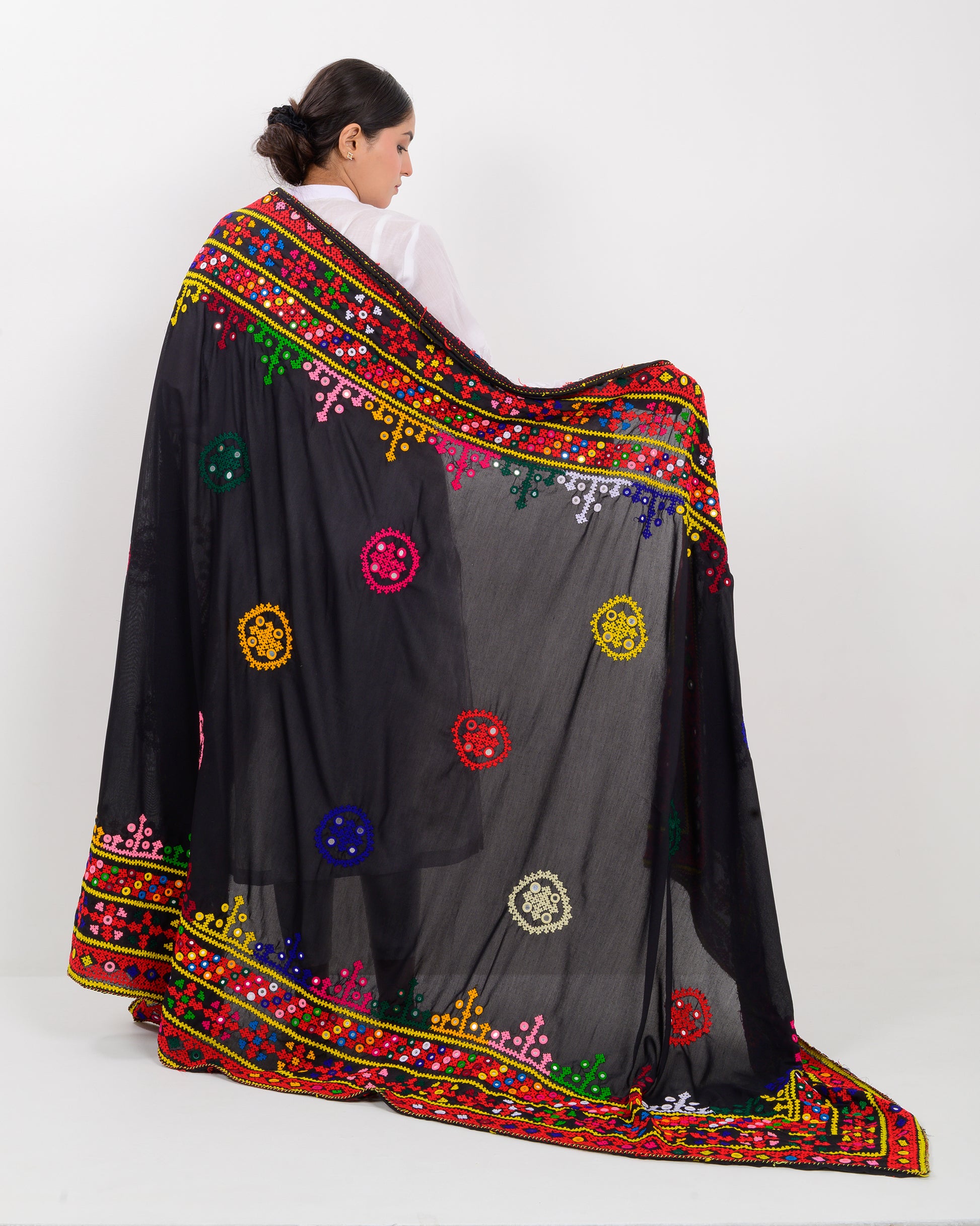 Woman wearing a black embroidered hummich mirror work shawl on a white background