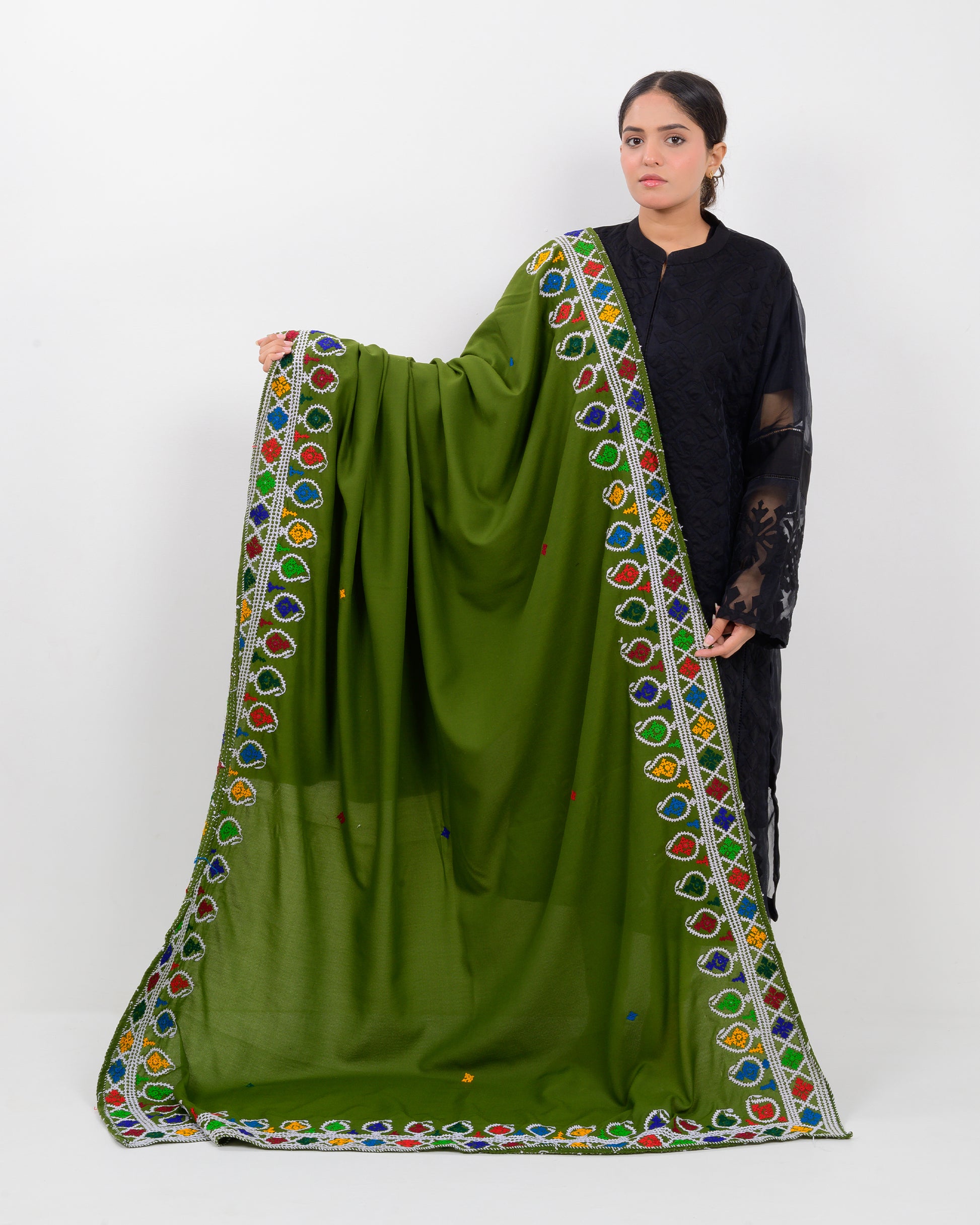 Woman holding a green hurmich embroidery shawl with black kurti on a white background