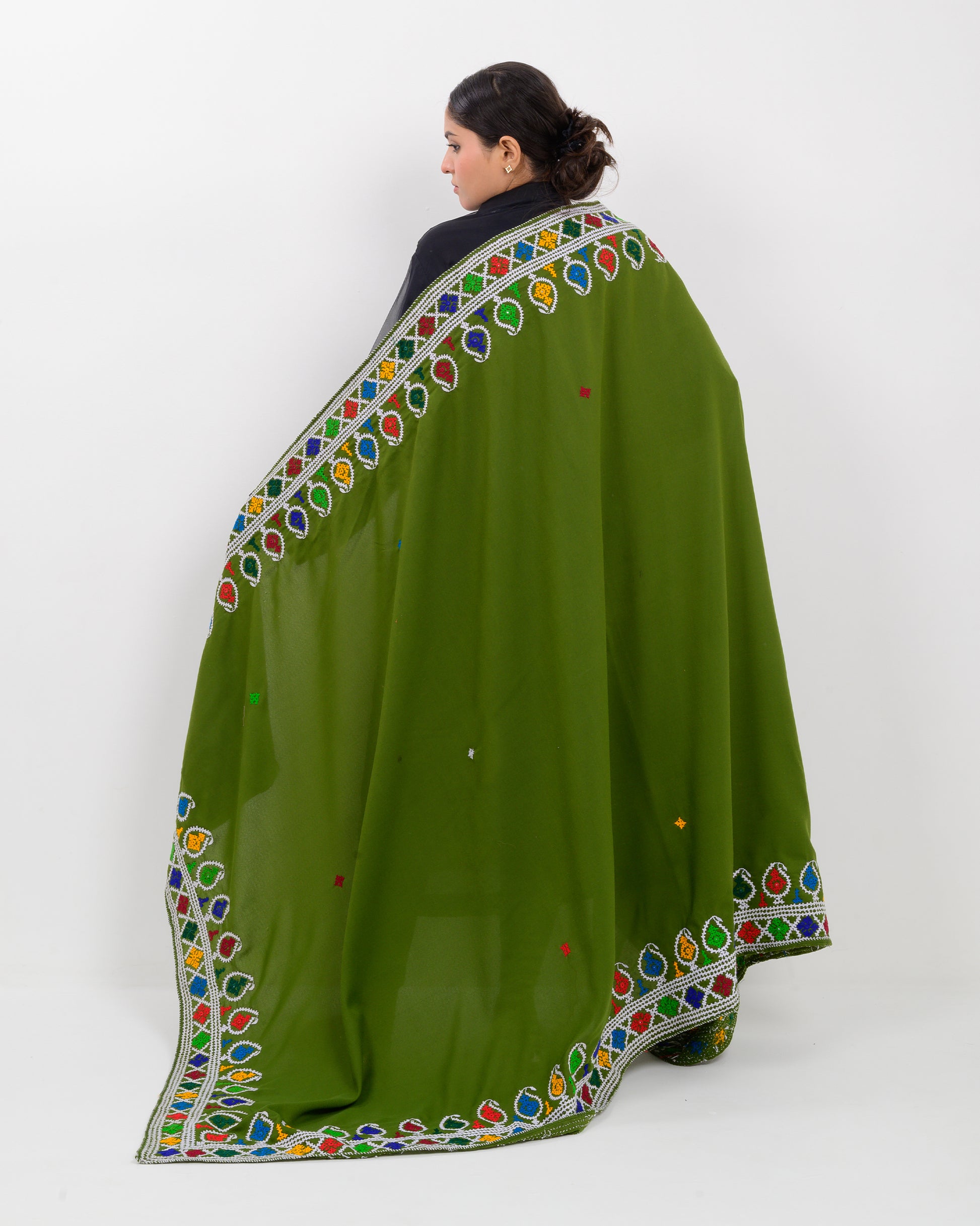 Woman holding a green hurmich embroidery shawl with black kurti on a white background