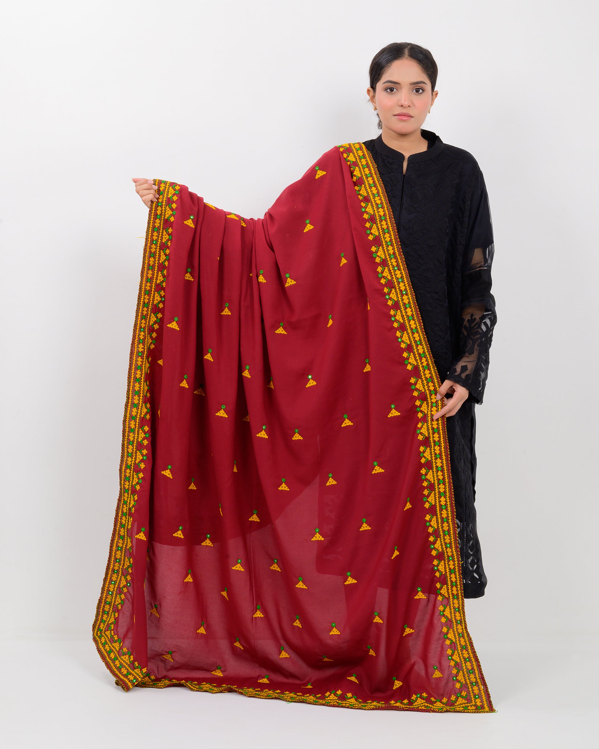 Woman holding a maroon color with yellow hurmich embroidery shawl on a white background