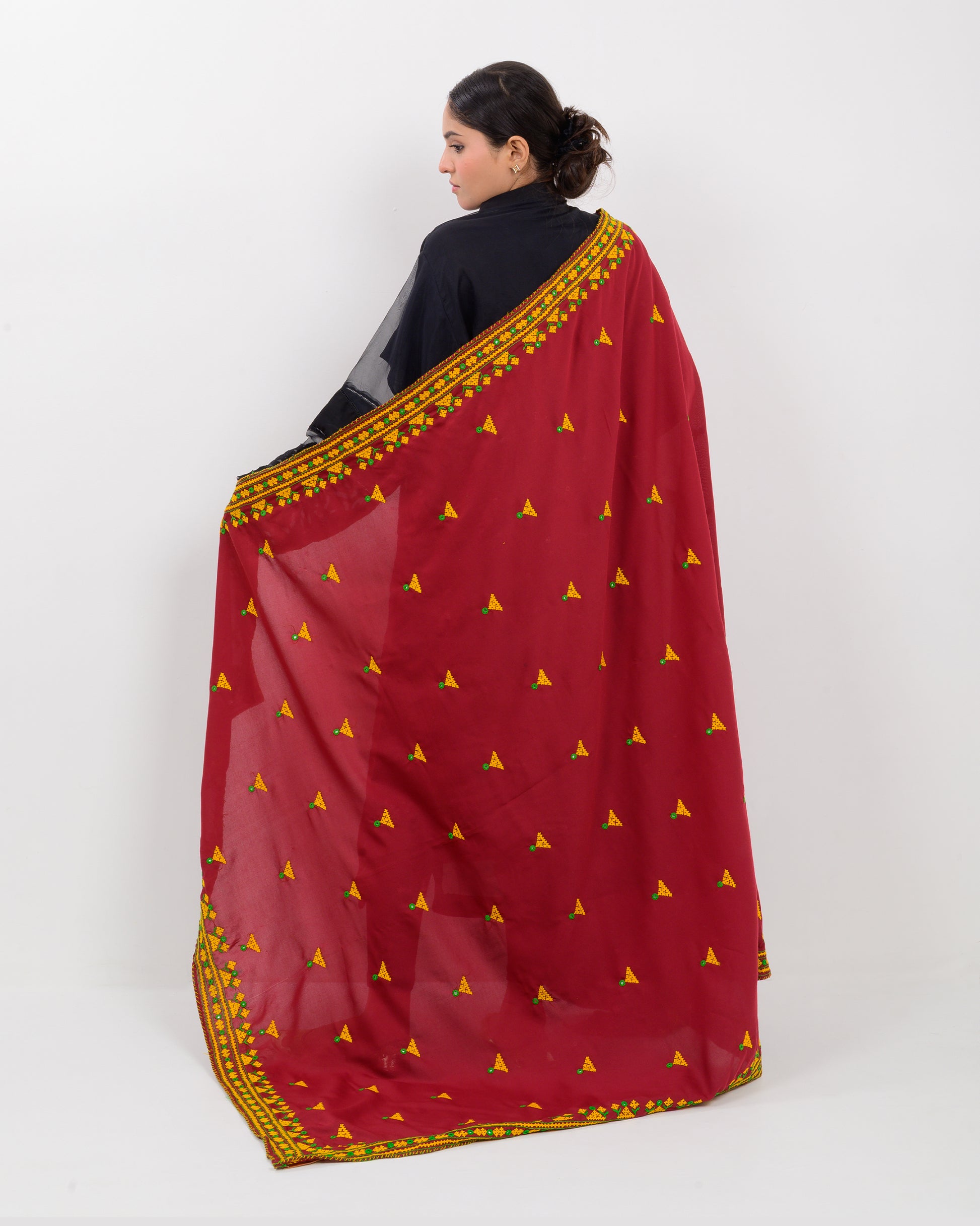 Woman holding a maroon color with yellow hurmich embroidery shawl on a white background