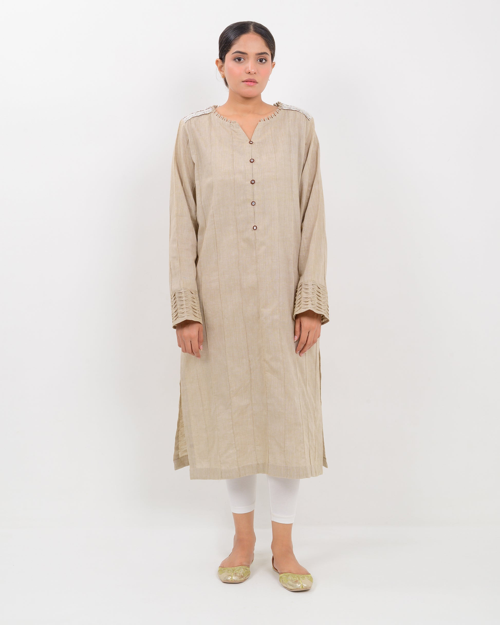 A woman wearing a kachi sui craft mirror work beige long shirt with white pants.