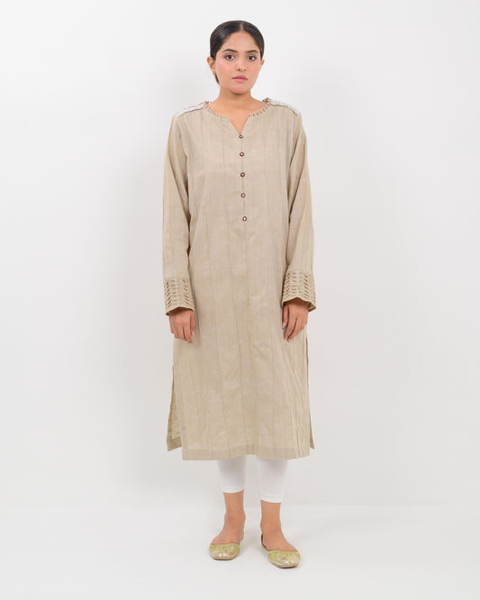 A woman wearing a kachi sui craft mirror work beige long shirt with white pants.
