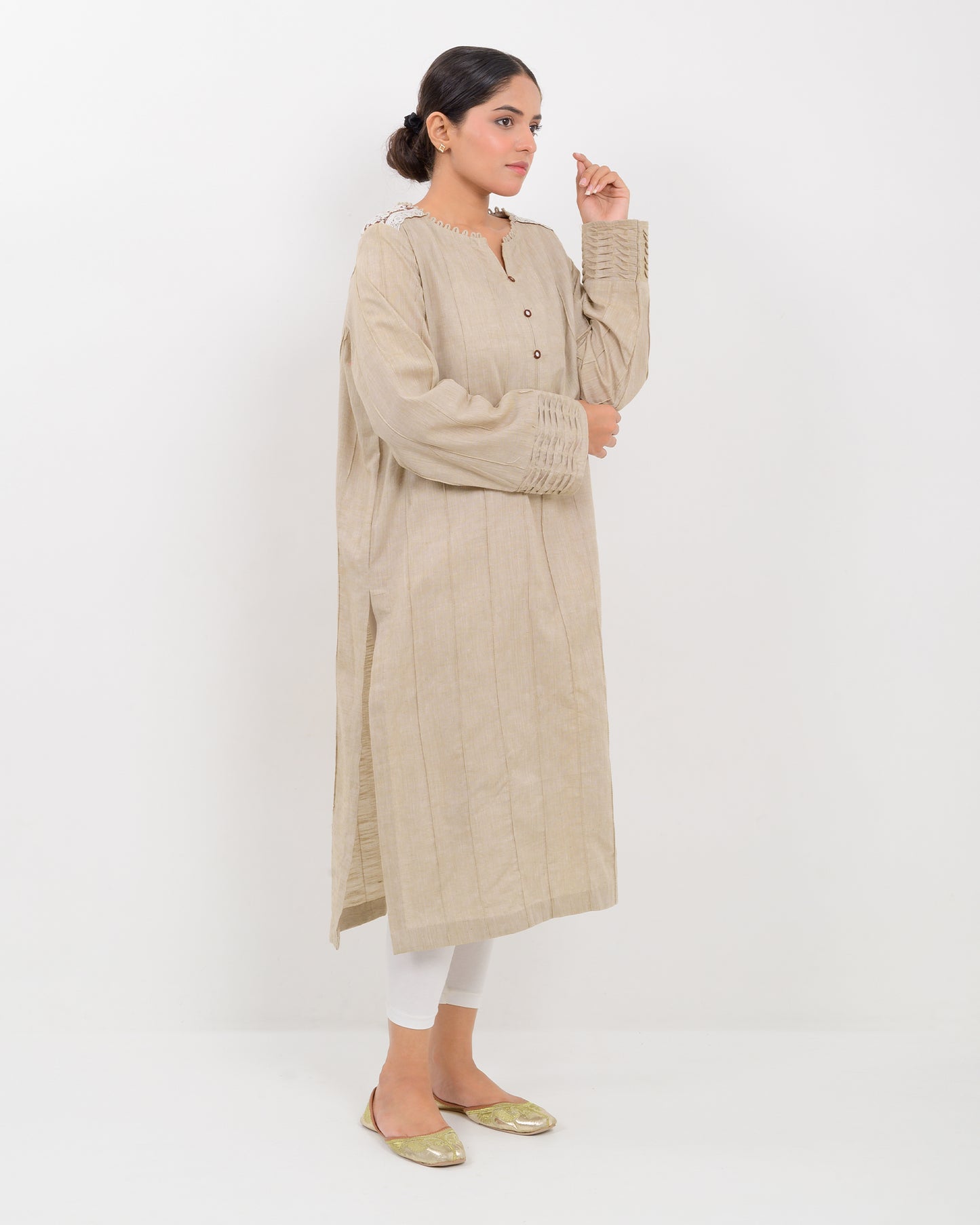 A woman wearing a kachi sui craft mirror work beige long shirt with white pants.