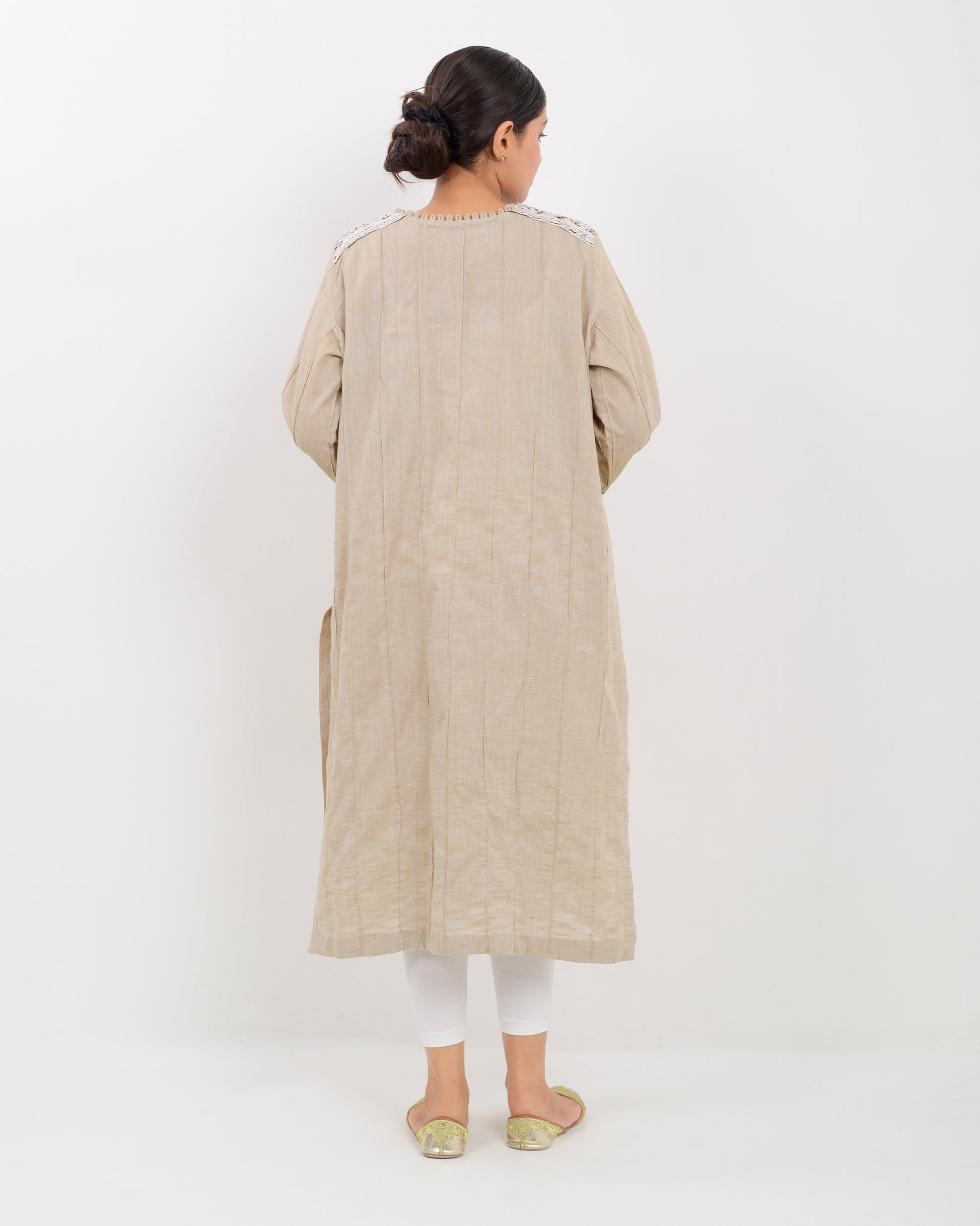 A woman wearing a kachi sui craft mirror work beige long shirt with white pants.