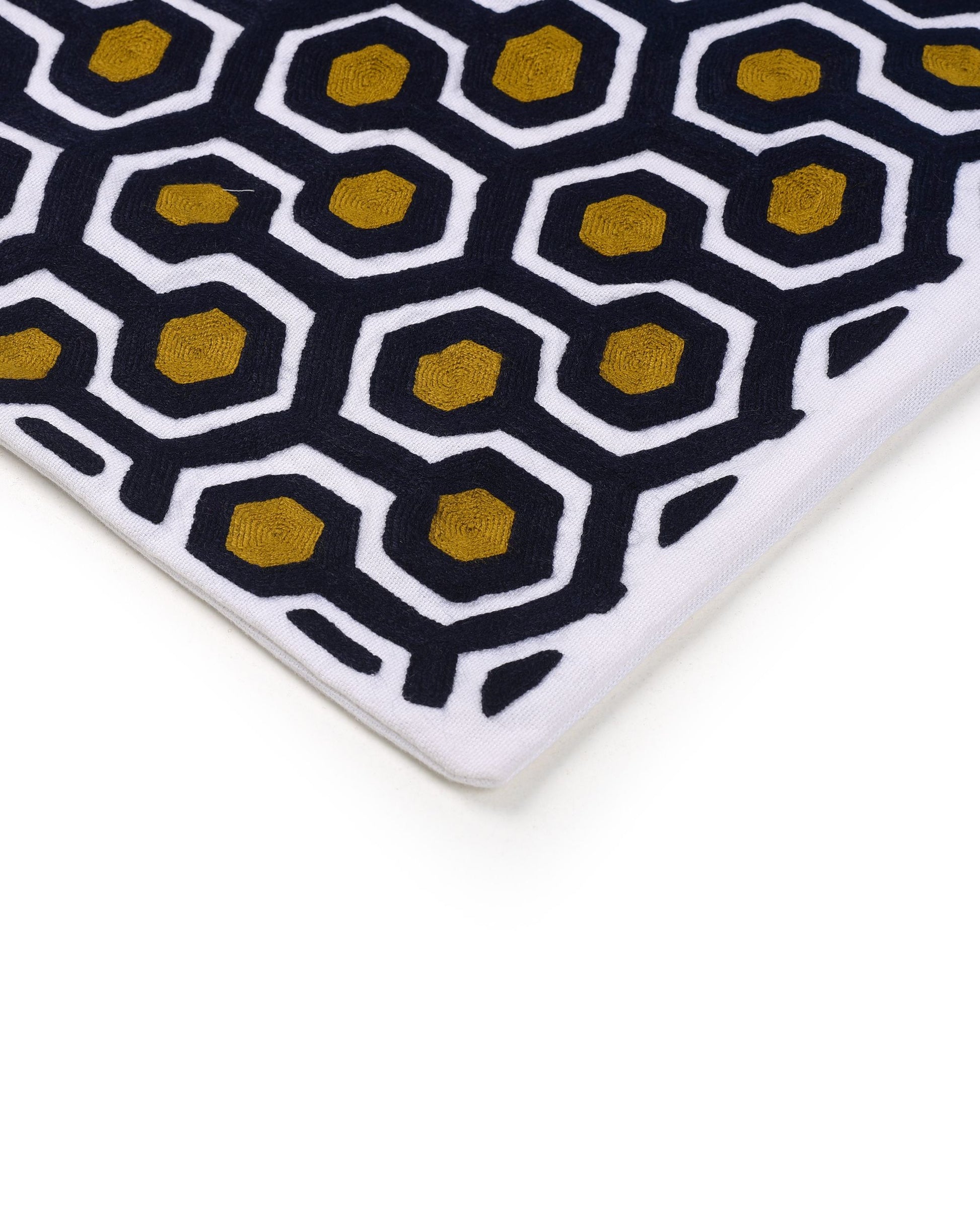 Close-up of a geometric-patterned cushion cover with black and gold hexagonal design on a white background
