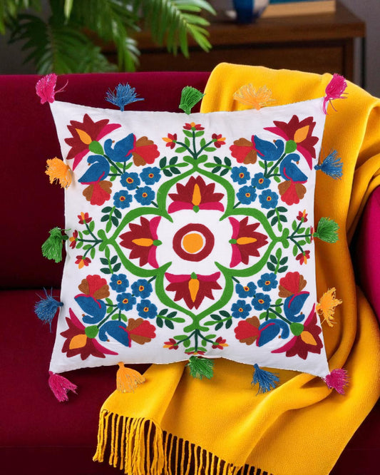 Decorative pillow with colorful floral patterns on a red couch with a yellow blanket.