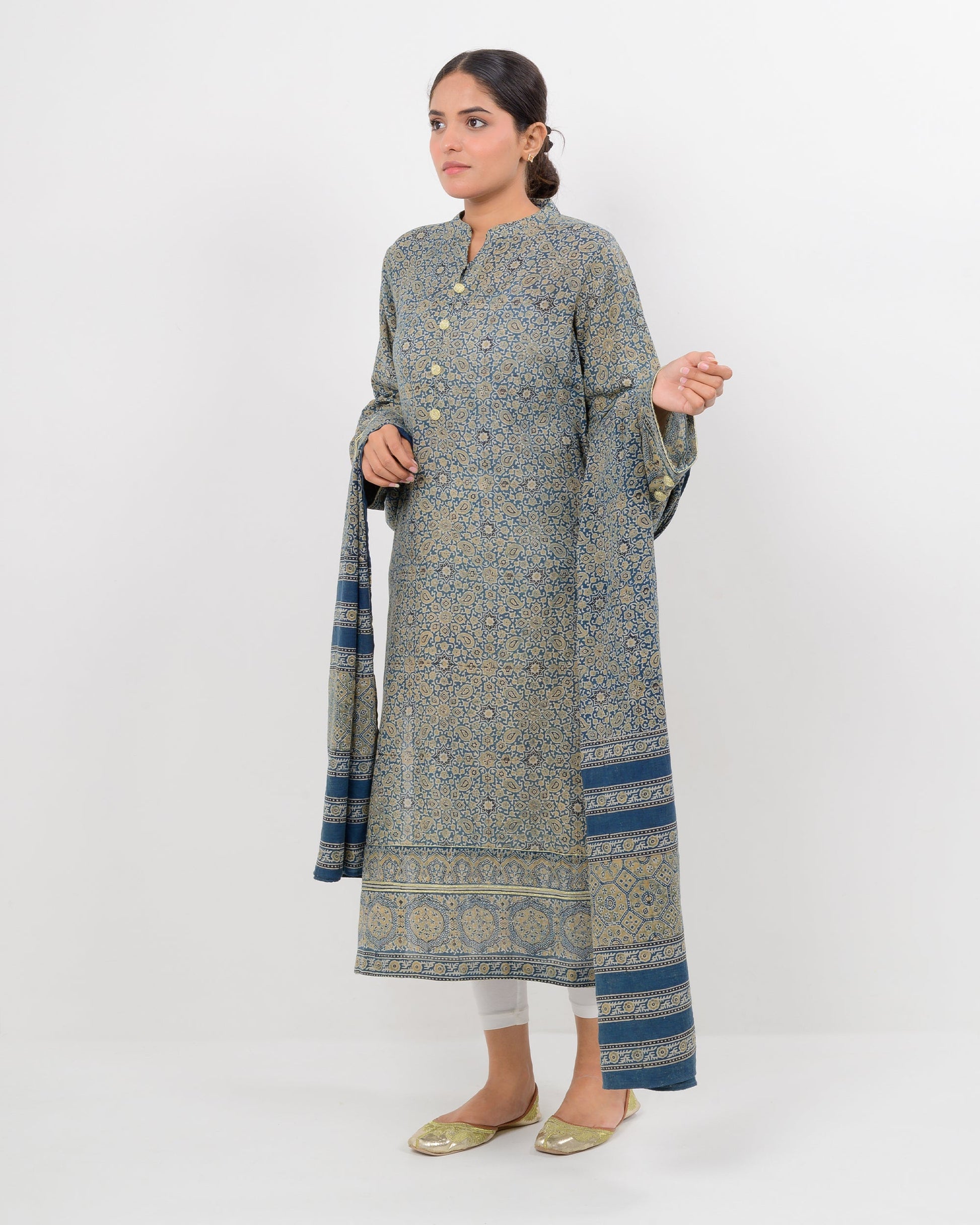 Woman wearing a long, patterned dress with a matching shawl on a white background