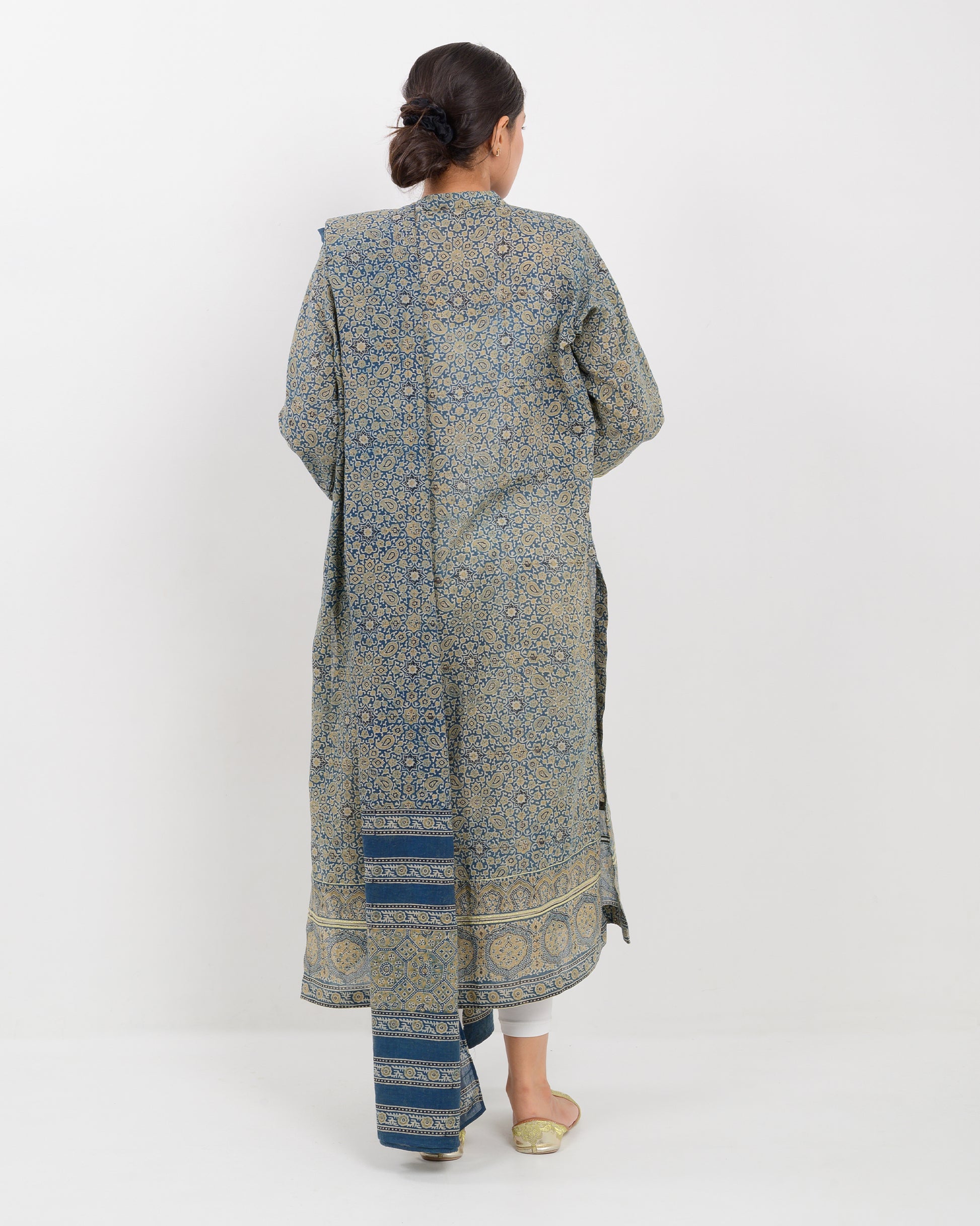 Woman wearing a long, patterned dress with a matching shawl on a white background