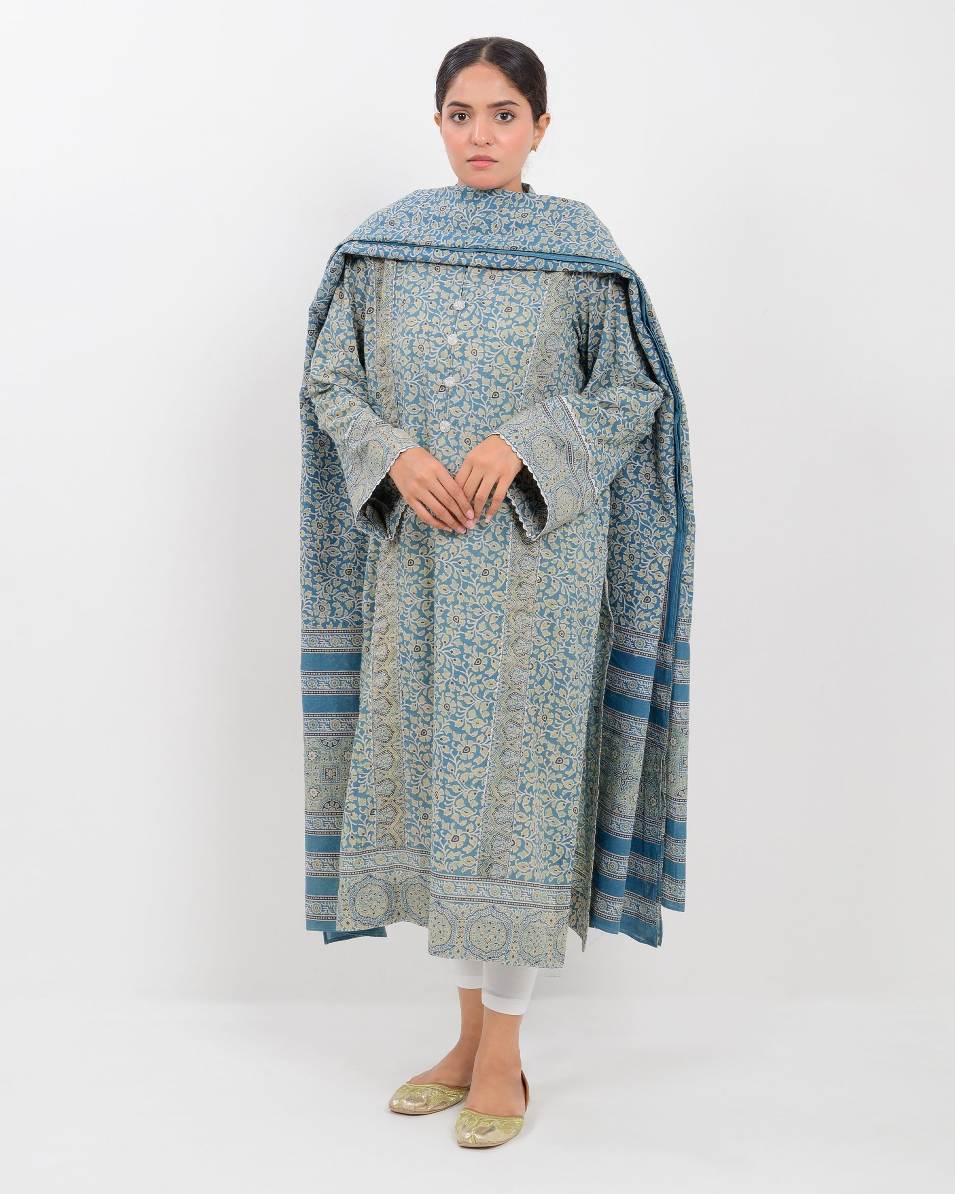 Woman wearing a long, patterned dress with a dupatta against a white background