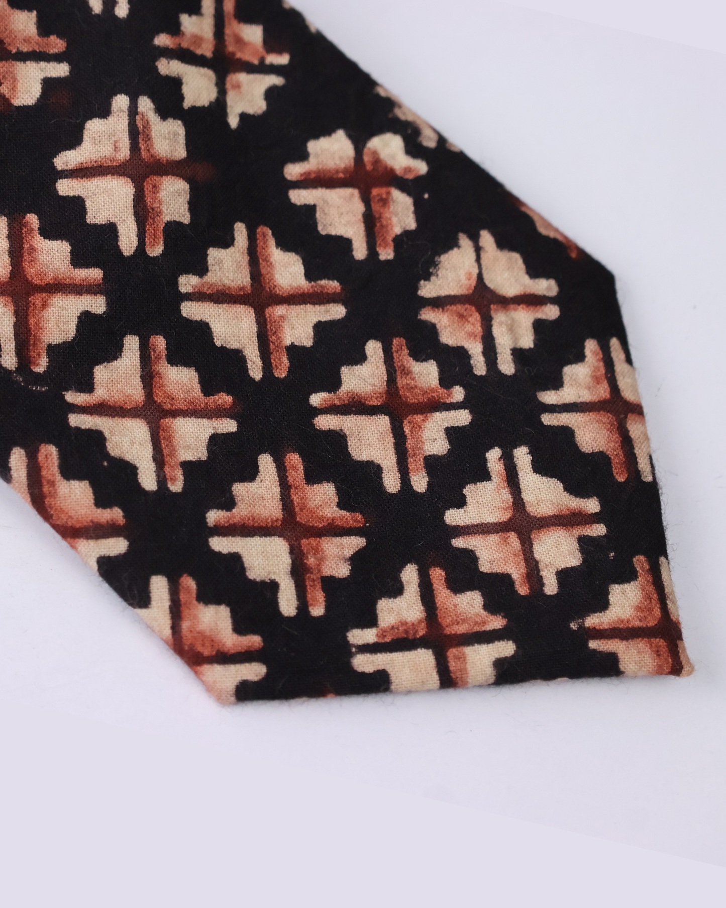 Natural dye hand block print cotton tie with near black base and sand camel burnt rust geometric cross diamond motifs handcrafted in Sindh Pakistan
