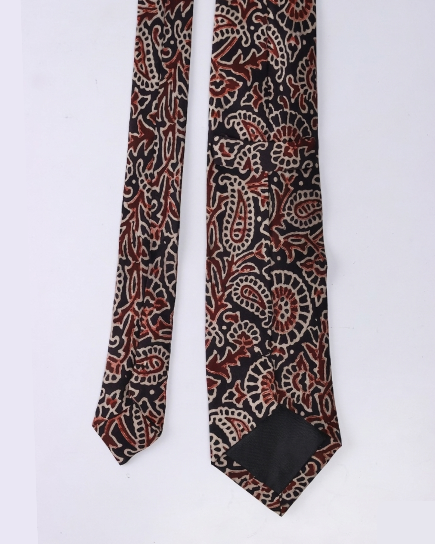 Natural dye hand block print silk tie with near black base and oversized paisley floral motifs in terracotta burnt sienna and antique cream handcrafted in Sindh Pakistan