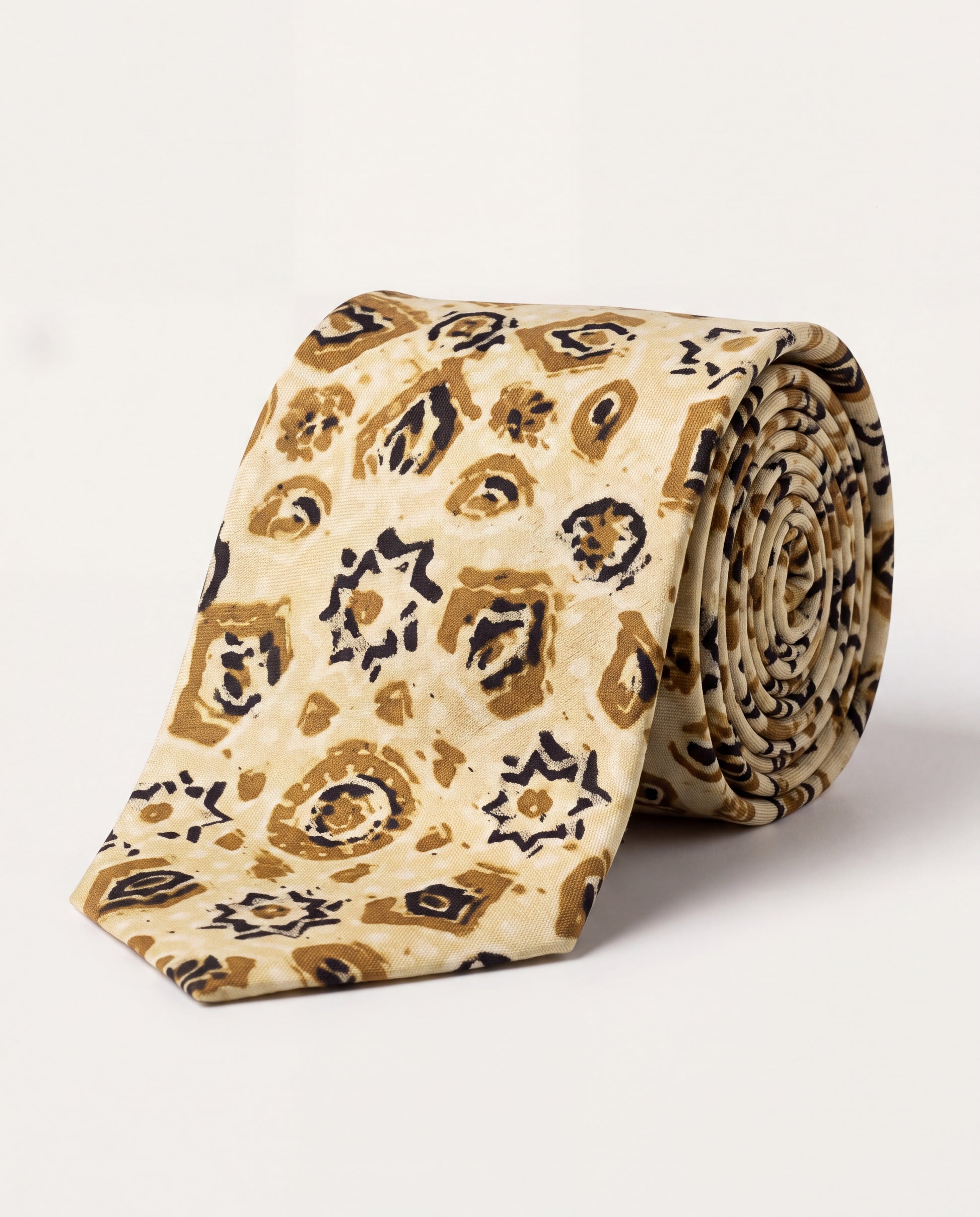A rolled silk necktie with a beige base and an abstract leopard-like print in brown and black, displayed on a clean white background.