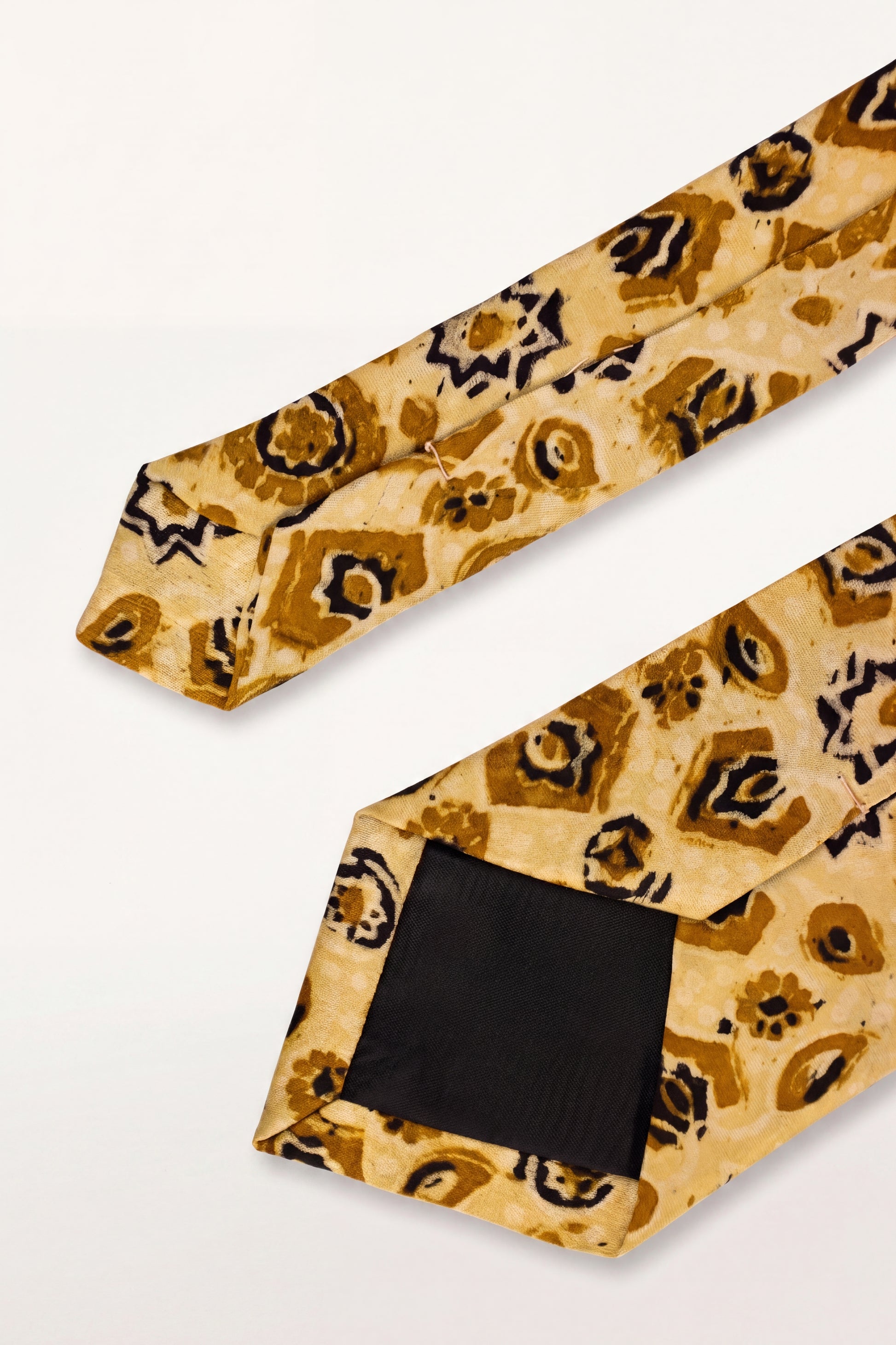 A silk necktie with a gold, brown, and black abstract leopard print pattern, displayed diagonally on a clean white background.