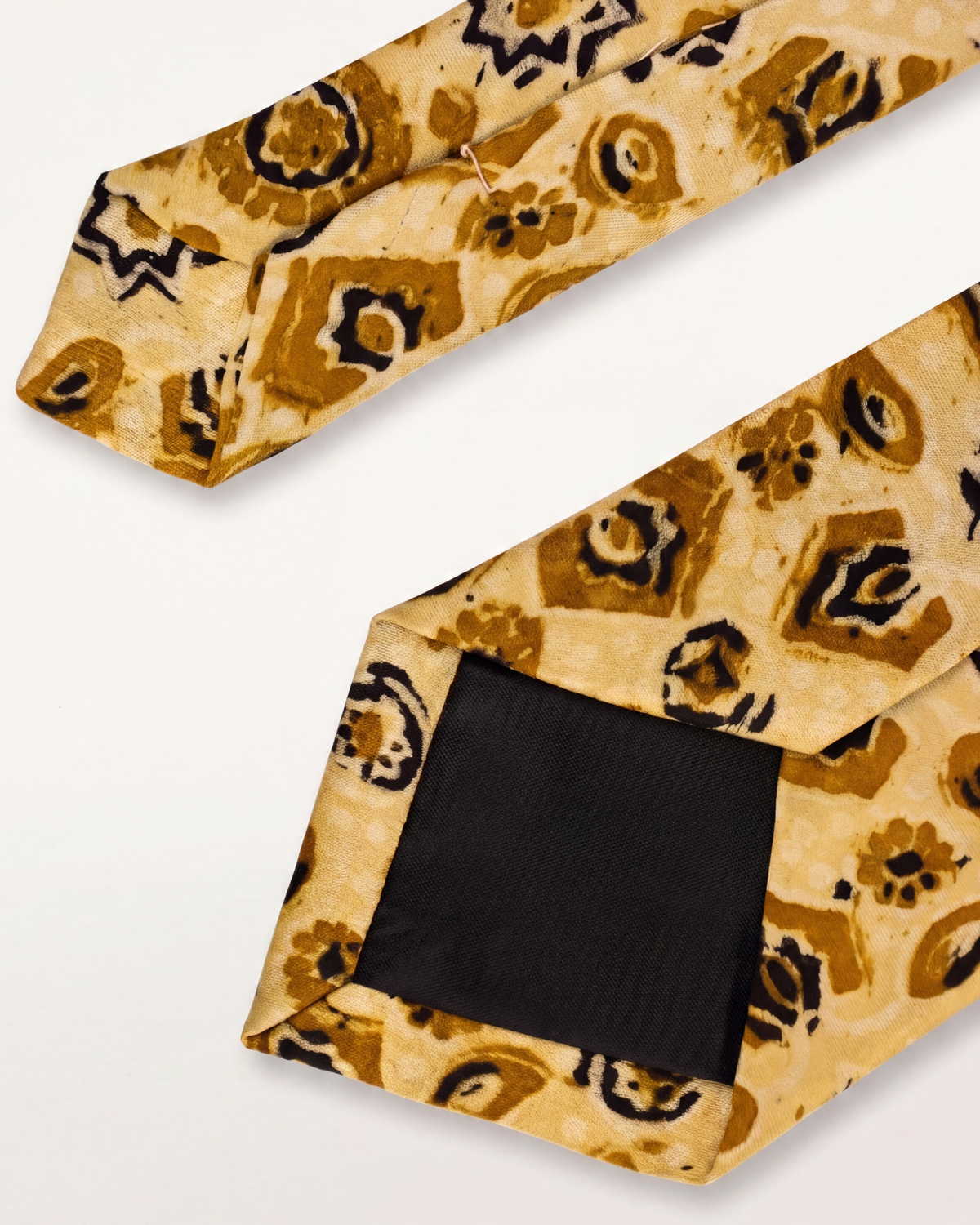 A patterned necktie with a beige base and brown and black abstract floral motifs, shown with the front and back folded over on a white background.