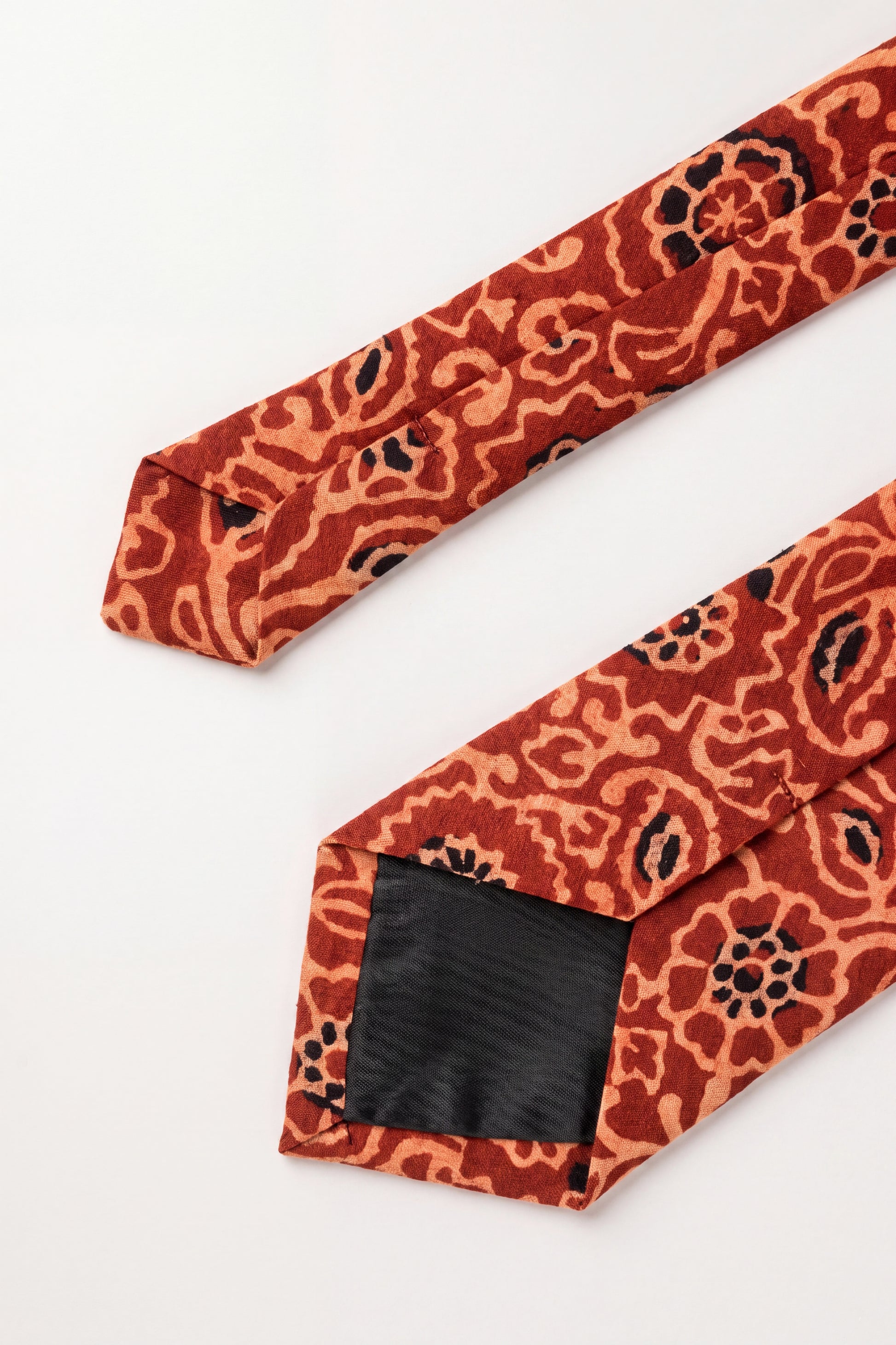 Handcrafted natural dye block print silk necktie in rust and terracotta floral pattern made from premium silk, displayed for luxury men's fashion.