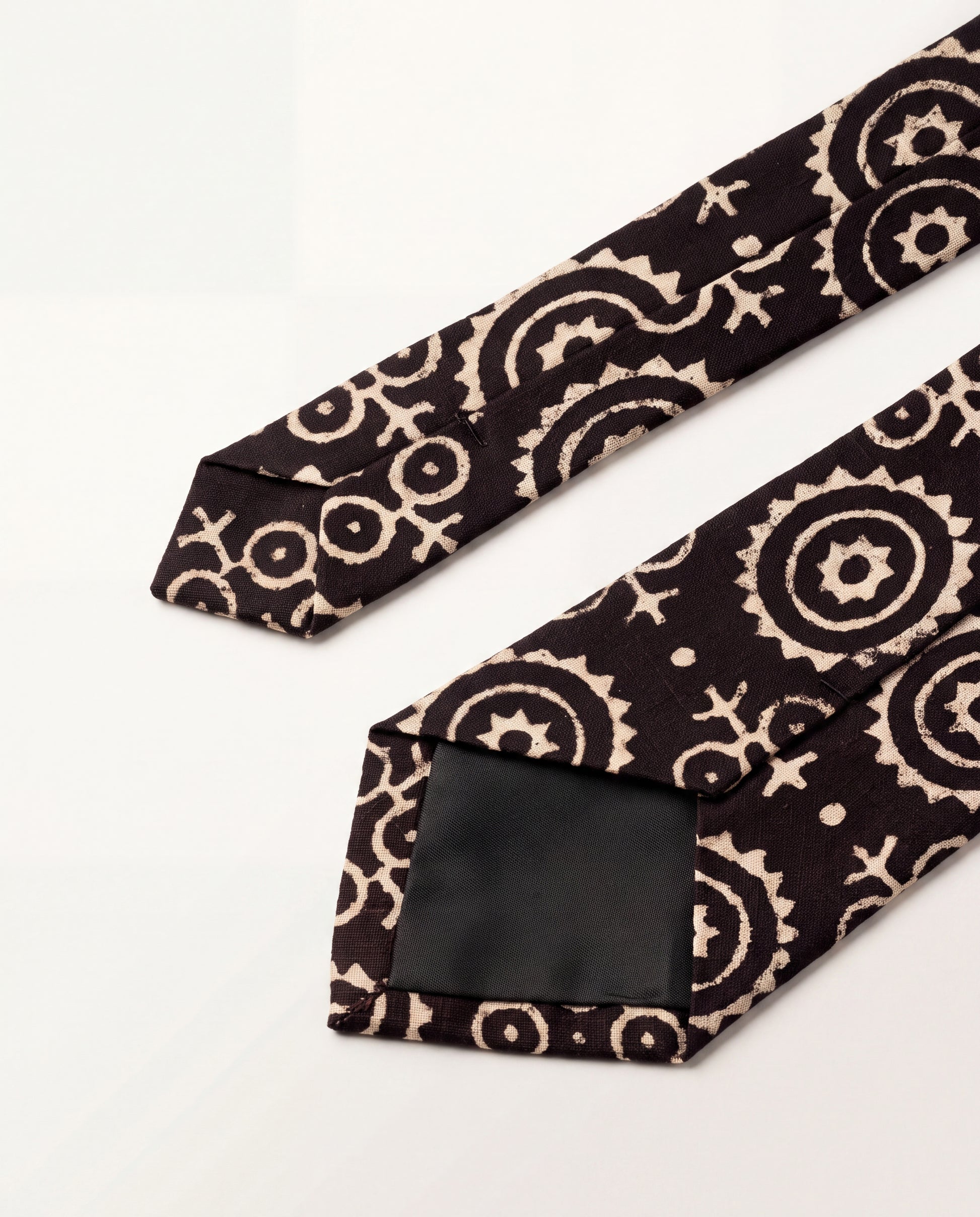 Lunar Eclipse natural dye Ajrak hand block print cotton tie in black with ivory geometric motifs, handcrafted by artisans in Sindh, Pakistan.