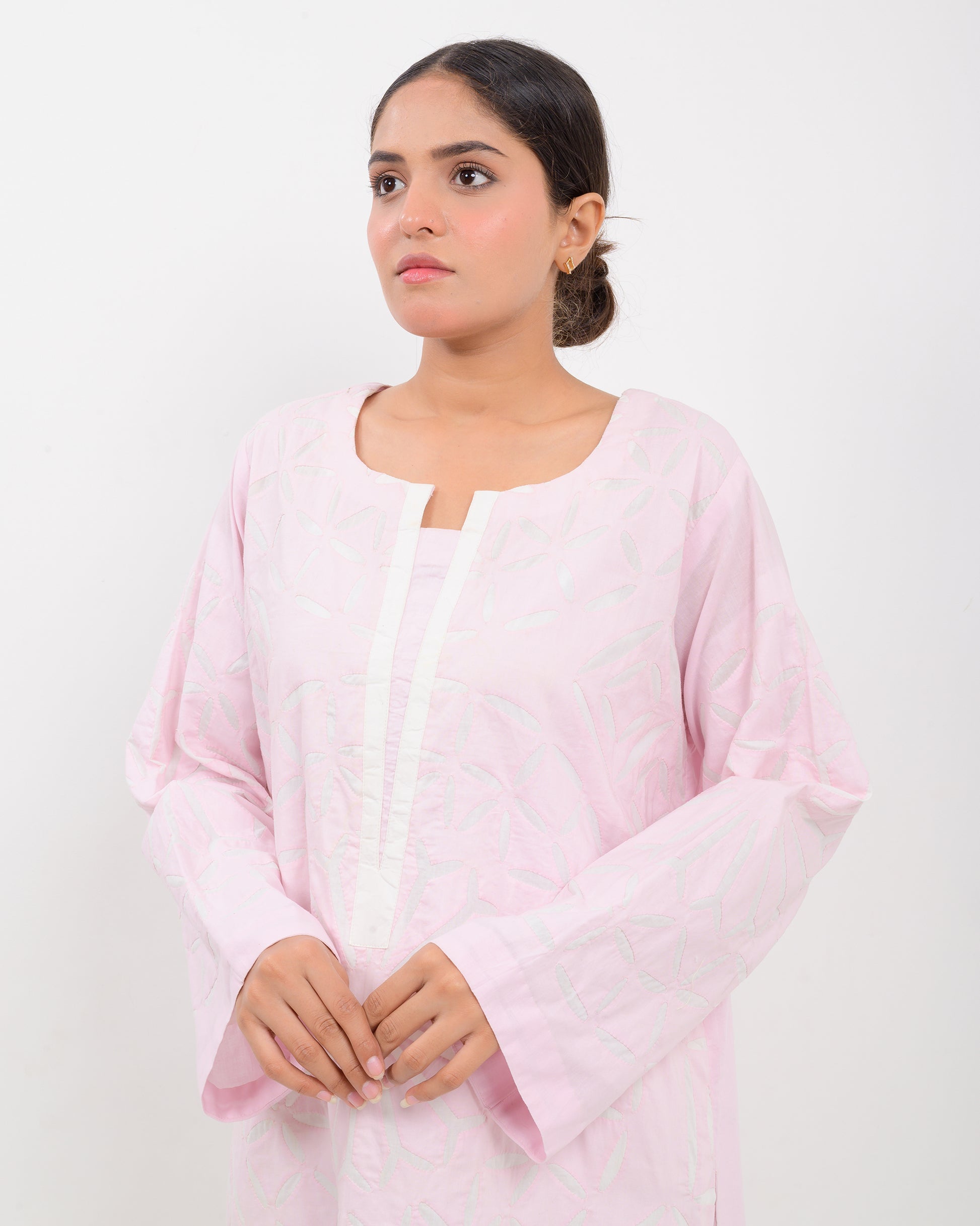 A woman wearing a light pink Applique cutwork Shirt with a white pants on a white background