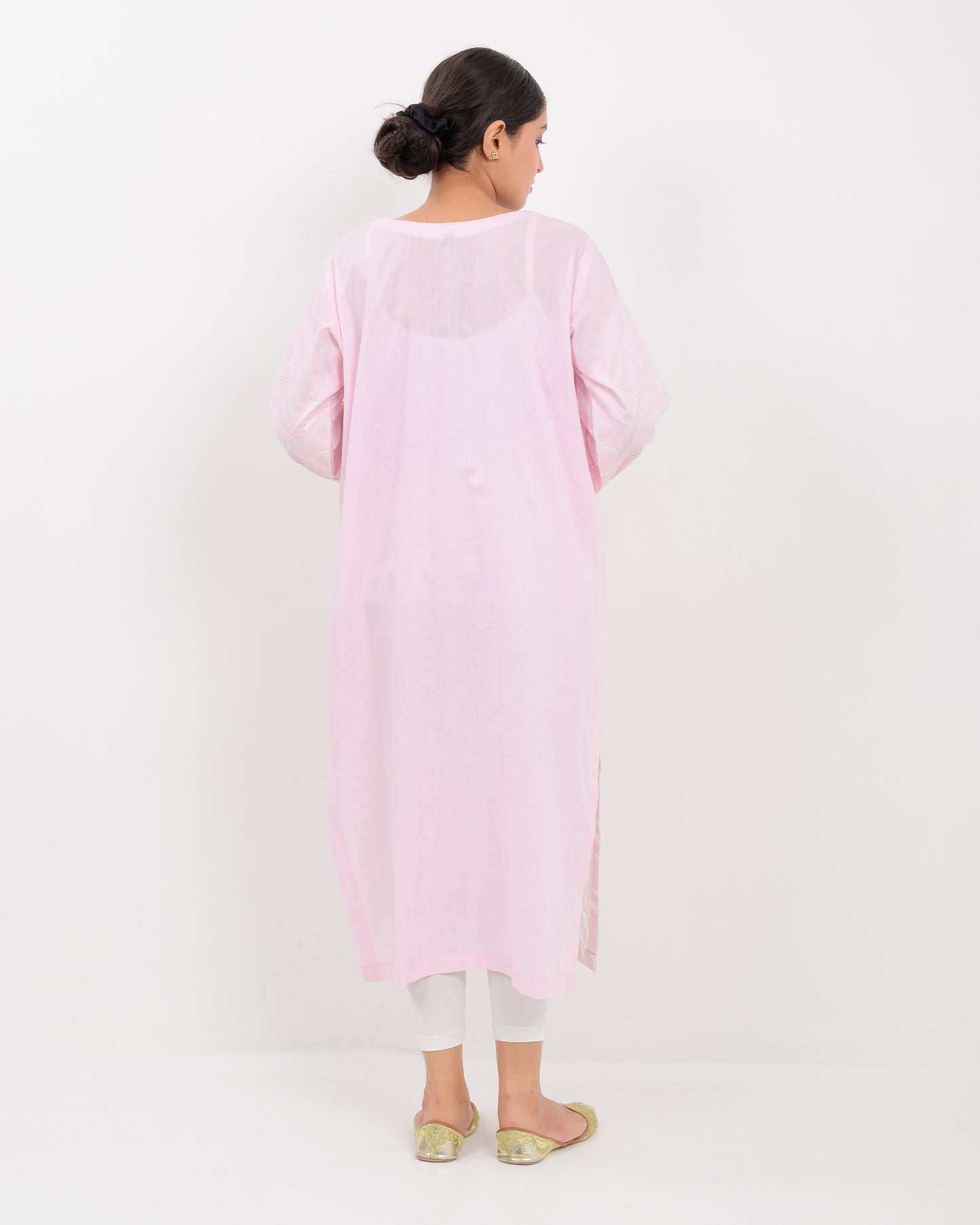 A woman wearing a light pink Applique cutwork Shirt with a white pants on a white background
