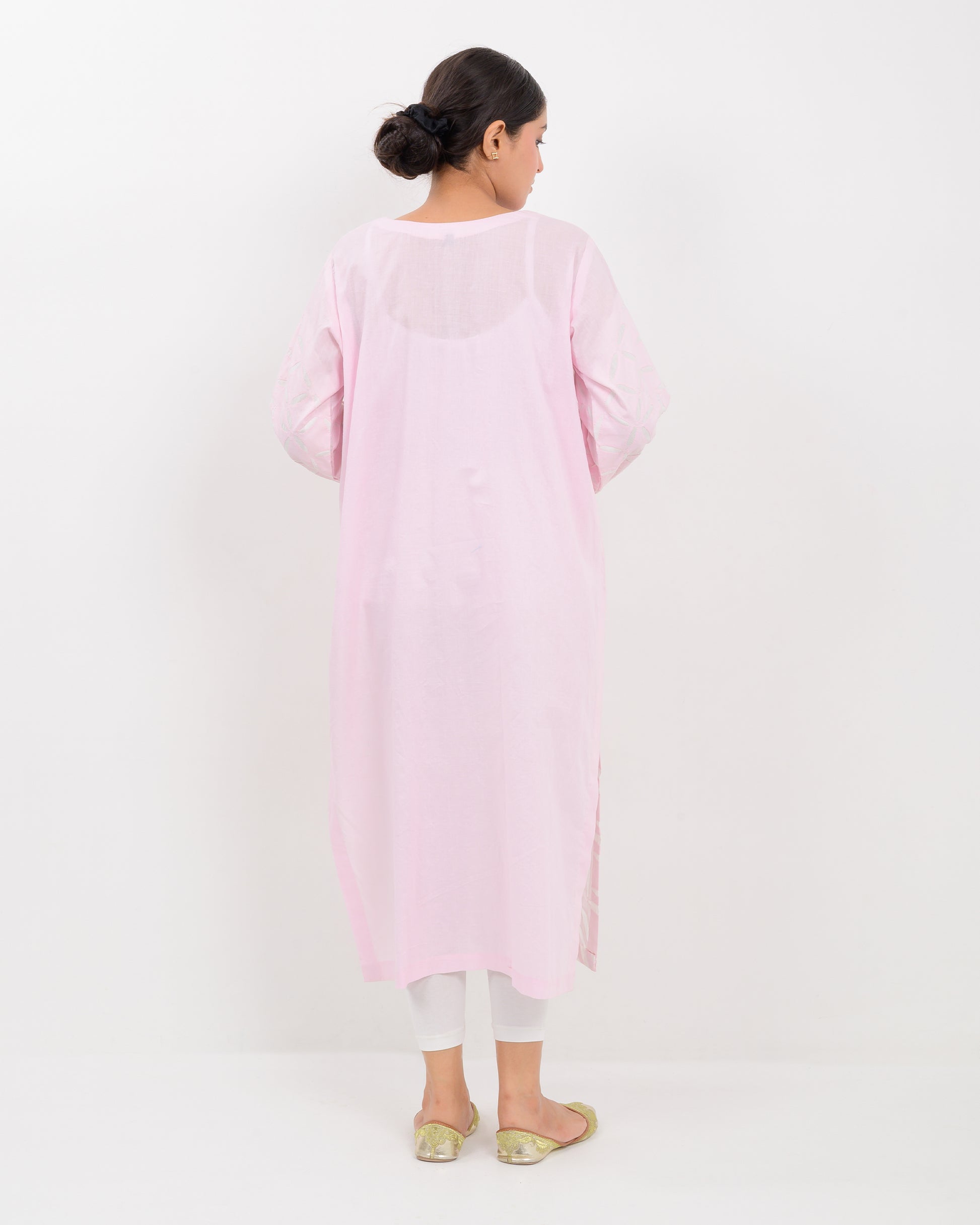 A woman wearing a light pink Applique cutwork Shirt with a white pants on a white background