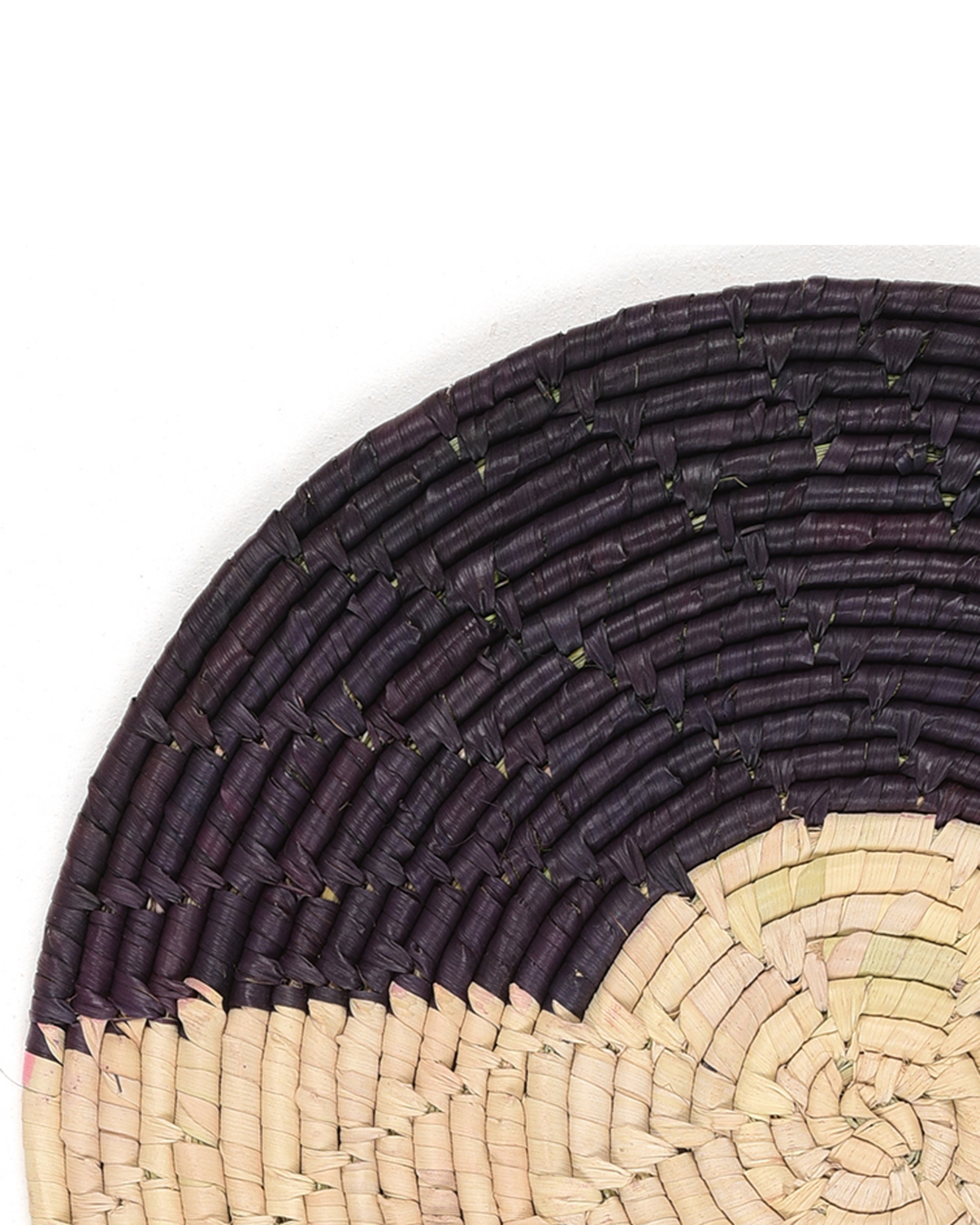 Close-up of a woven placemat with black and beige pattern on a white background