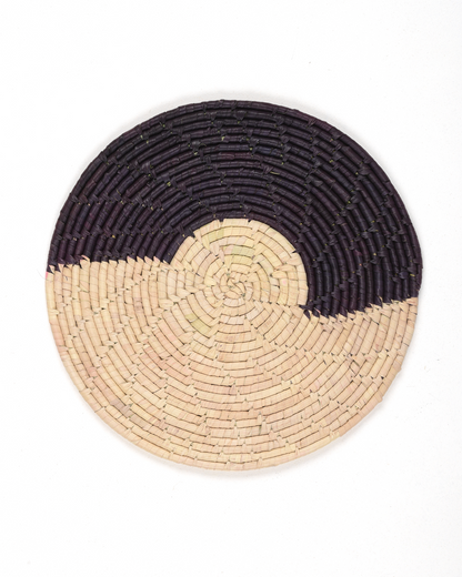 Round woven placemat with black and beige design on a white background