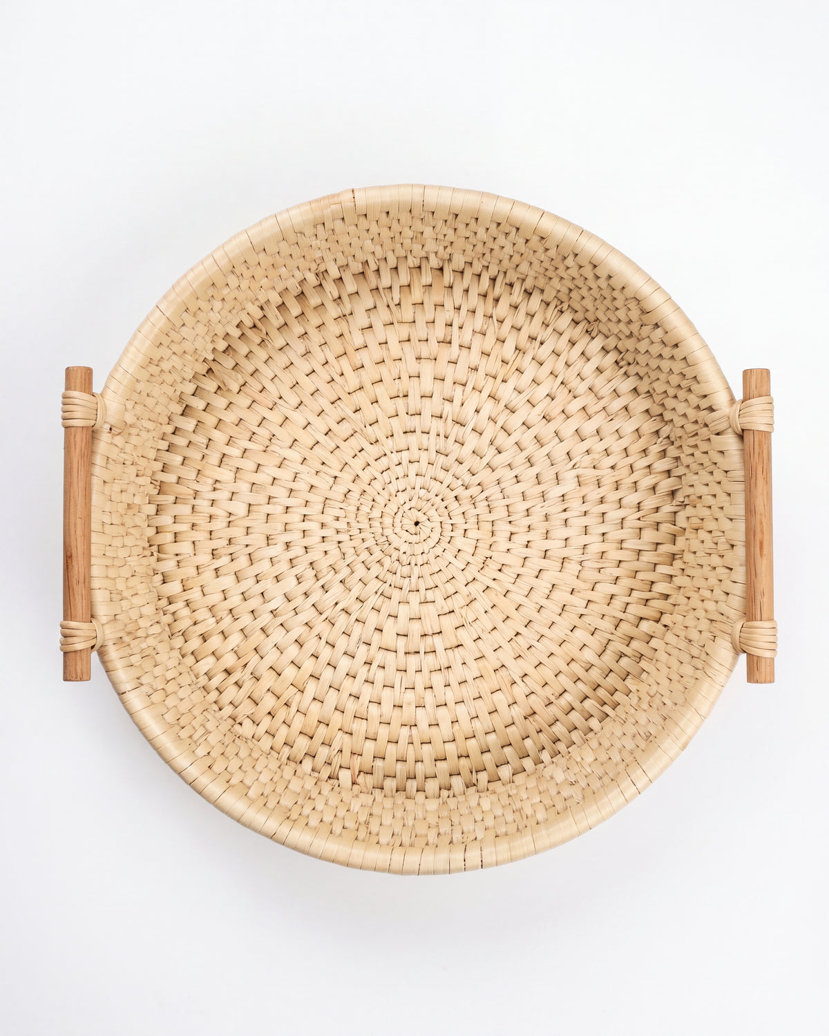 A round woven natural rattan basket with two wooden side handles, photographed from directly above on a clean white background.