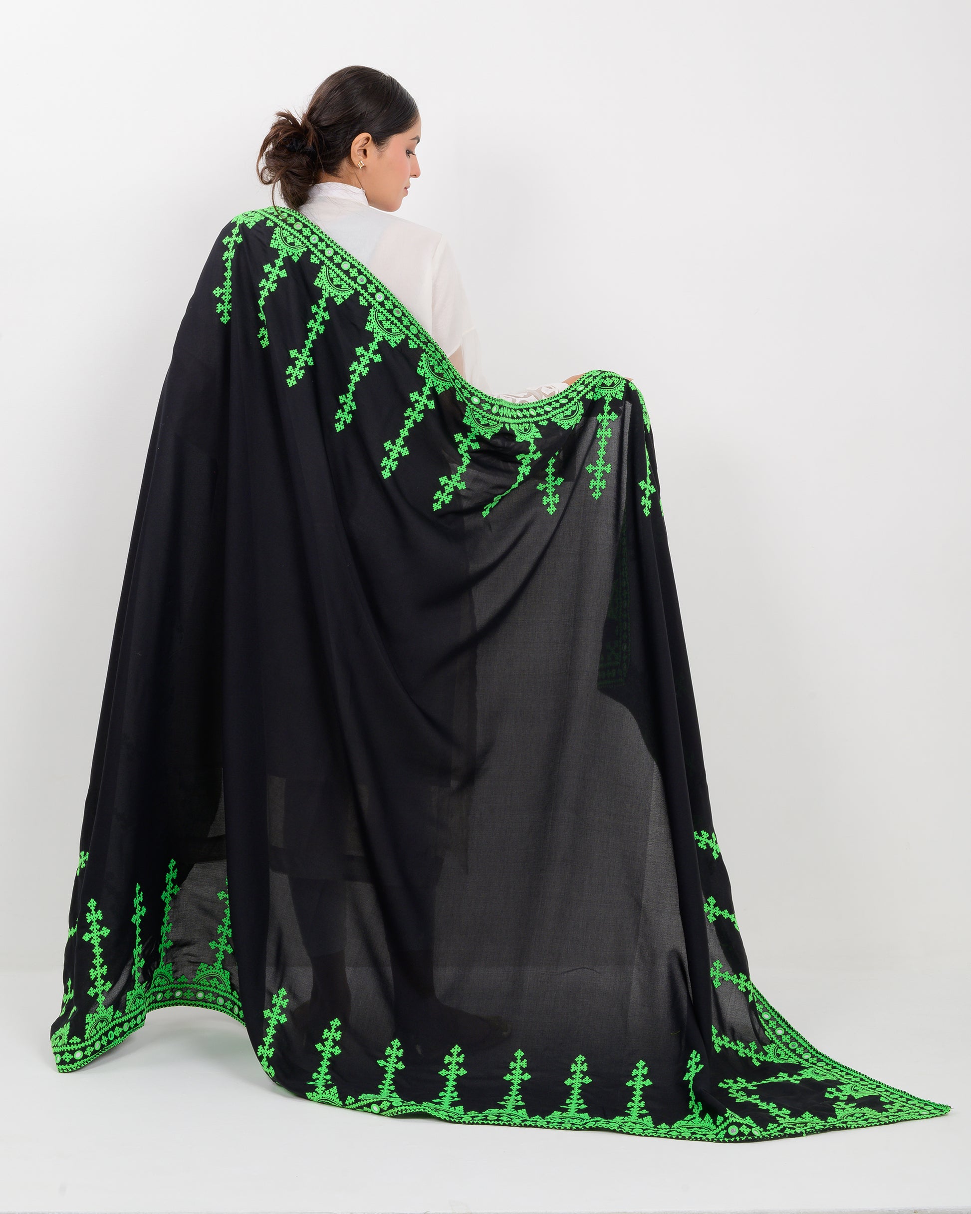 Woman wearing a black color with green hurmich embroidery shawl on a white background